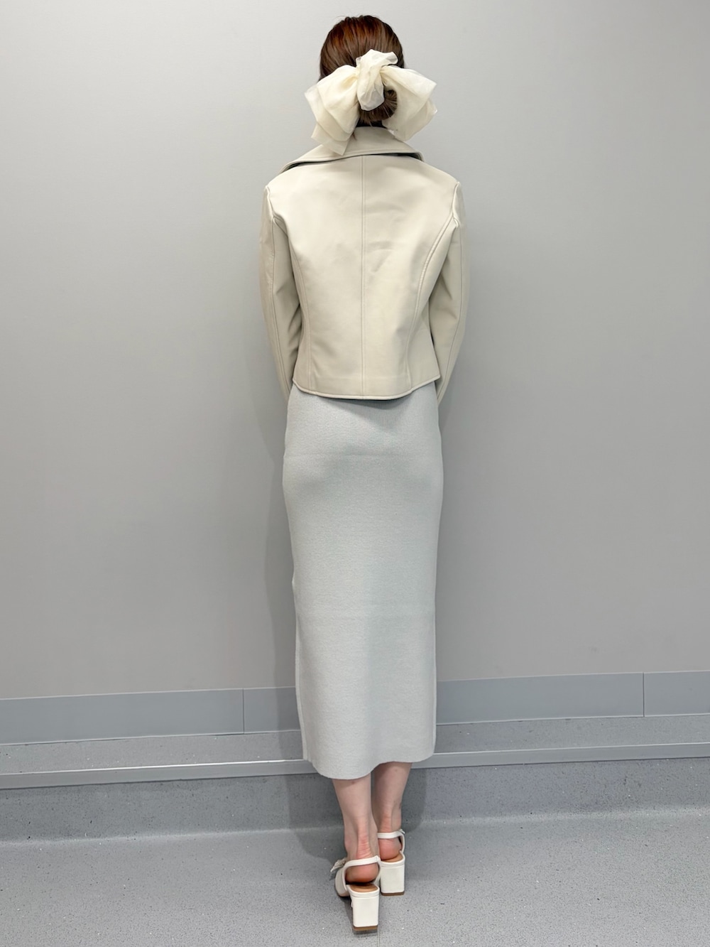 ホワイト系のライダースジャケット、ホワイト系のパンプス、グリーン系のワンピースを着用したレディースの冬コーディネートの6枚目の写真