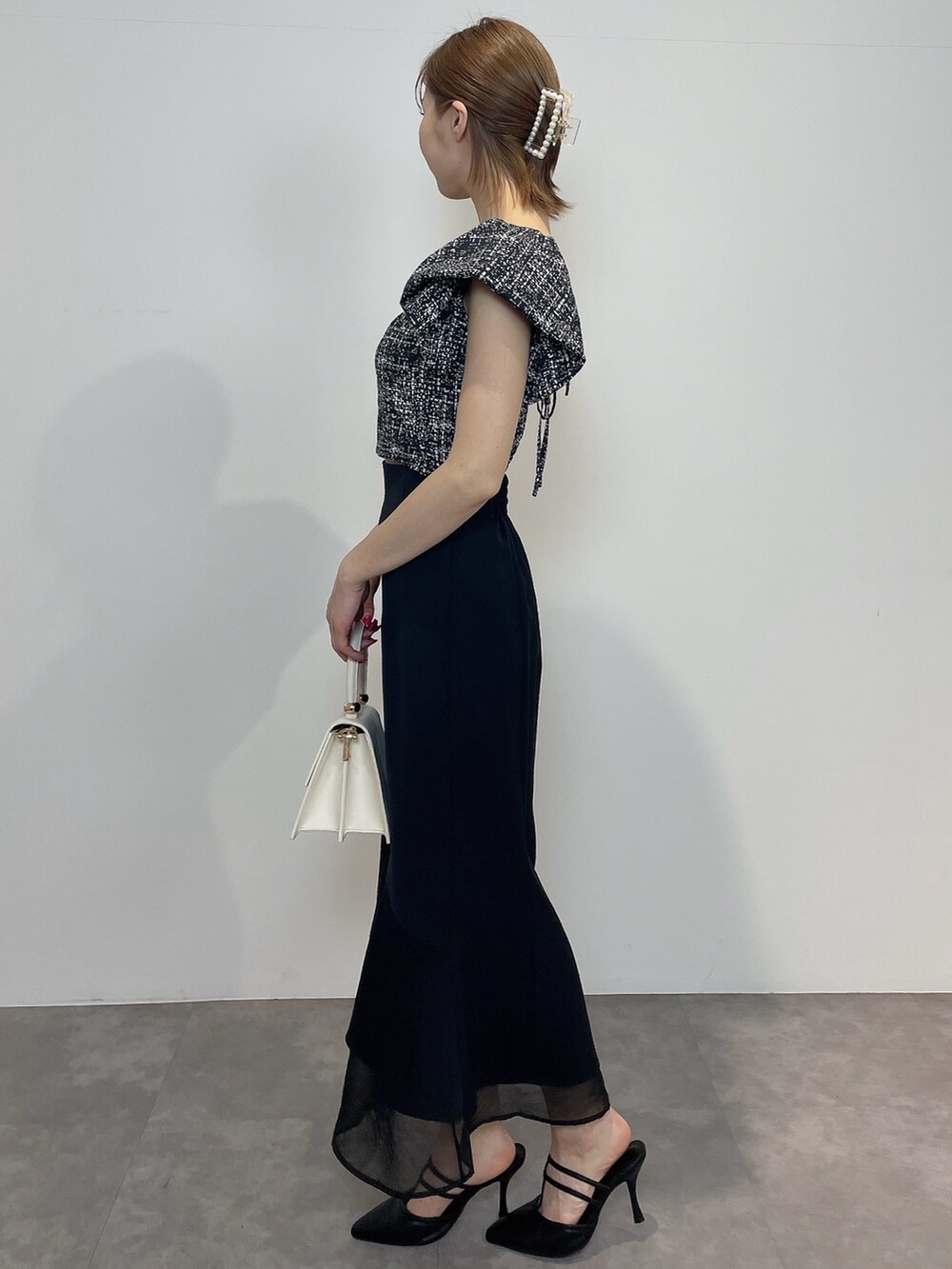 ブラック系のシャツ/ブラウス、ホワイト系のハンドバッグ、ブラック系のパンプスを着用したレディースの春コーディネートの4枚目の写真