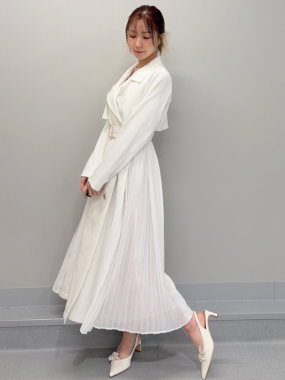 ホワイト系のトレンチコート、ピンク系のショルダーバッグ、オレンジ系のワンピースを着用したレディースの冬コーディネートの4枚目の写真