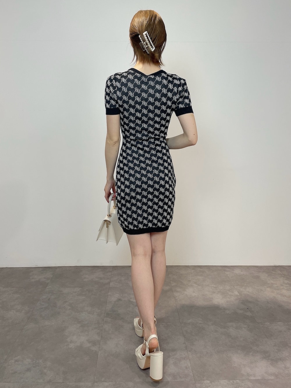 ホワイト系のハンドバッグ、ホワイト系のサンダル、ブラック系のワンピースを着用したレディースの春コーディネートの3枚目の写真