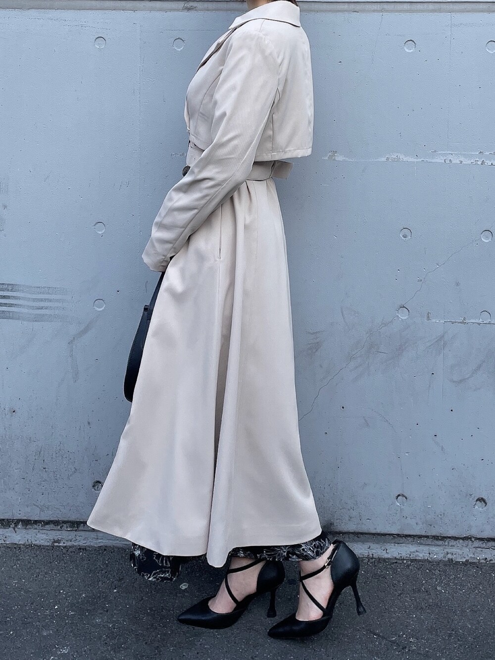 ベージュ系のトレンチコート、ブラック系のワンピース、ブラック系のハンドバッグを着用したレディースの冬コーディネートの6枚目の写真