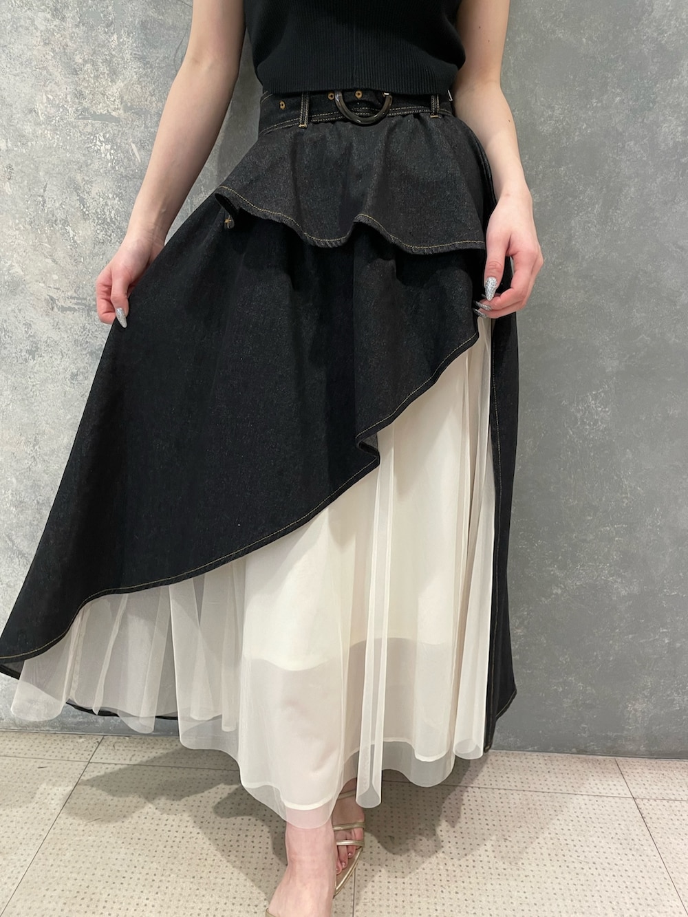 ブラック系のタンクトップ、ブラック系のデニムスカート、ゴールド系のサンダルを着用したレディースの春コーディネートの7枚目の写真