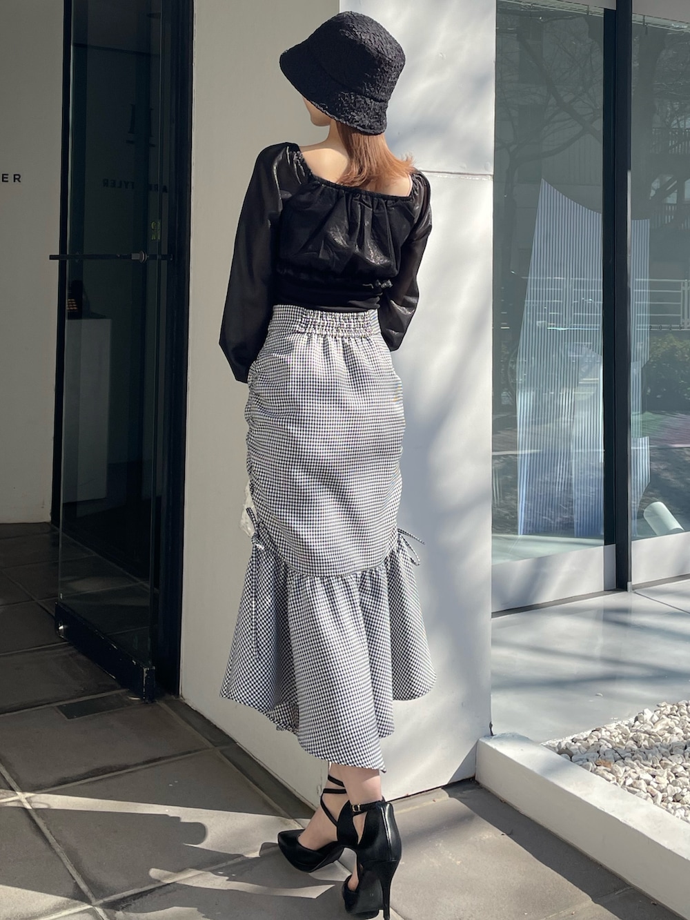 ホワイト系のハンドバッグ、ブラック系のパンプス、その他のスカートを着用したレディースの冬コーディネートの3枚目の写真