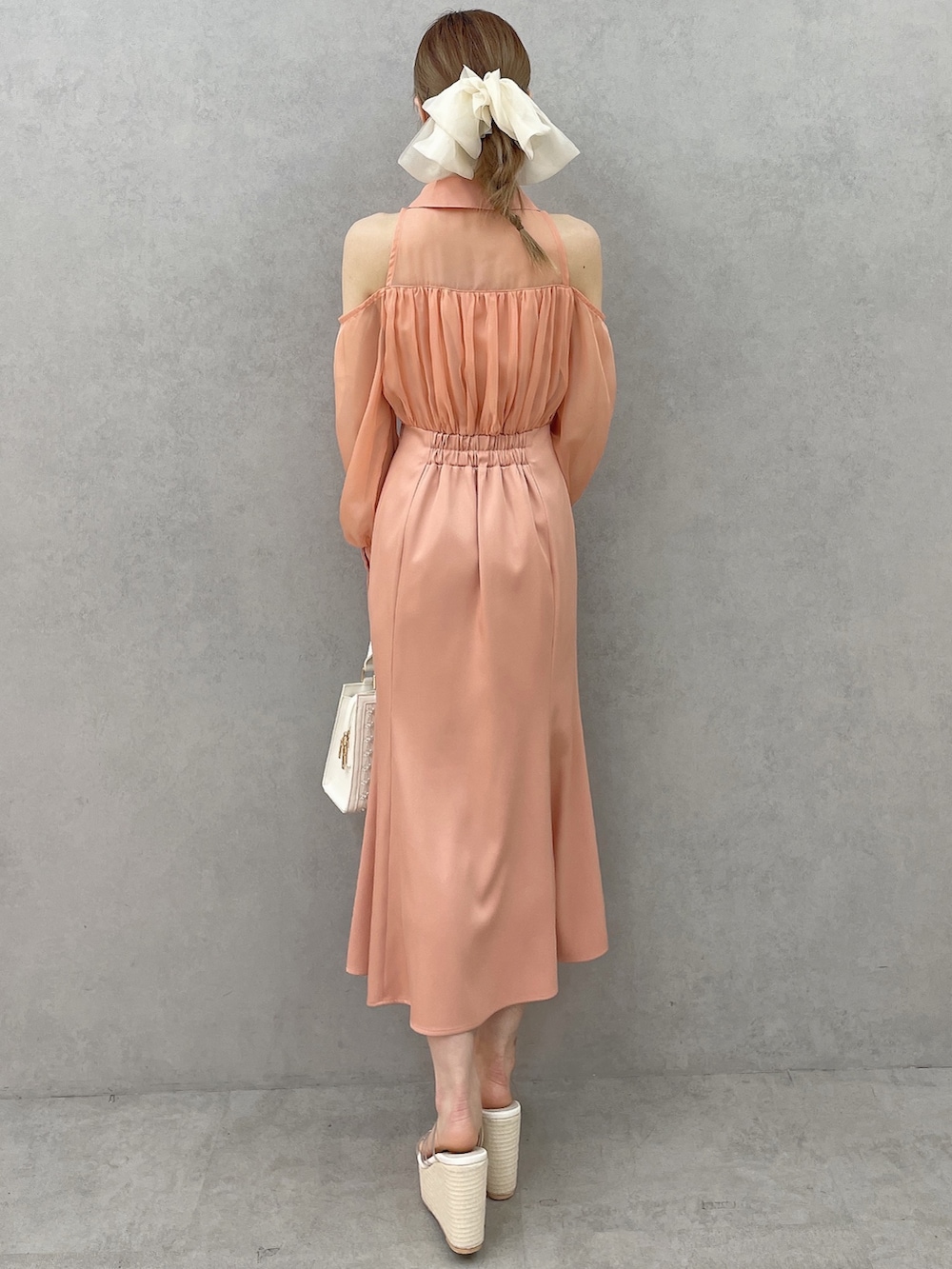 オレンジ系のワンピース、ホワイト系のハンドバッグ、ホワイト系のサンダルを着用したレディースの春コーディネートの4枚目の写真