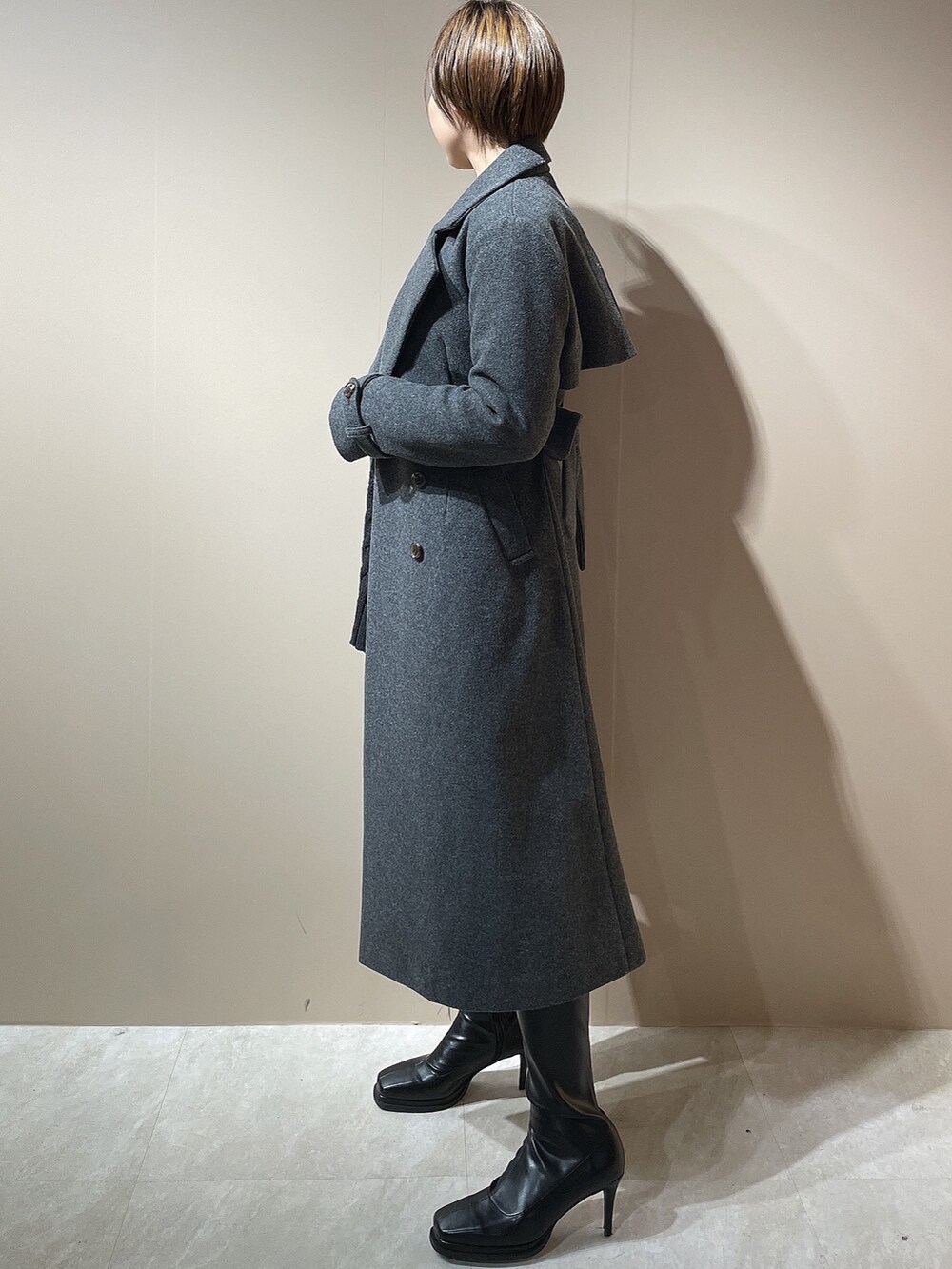 ブラック系のニット/セーター、グレー系のチェスターコート、ブラック系のブーツを着用したレディースの秋コーディネートの3枚目の写真