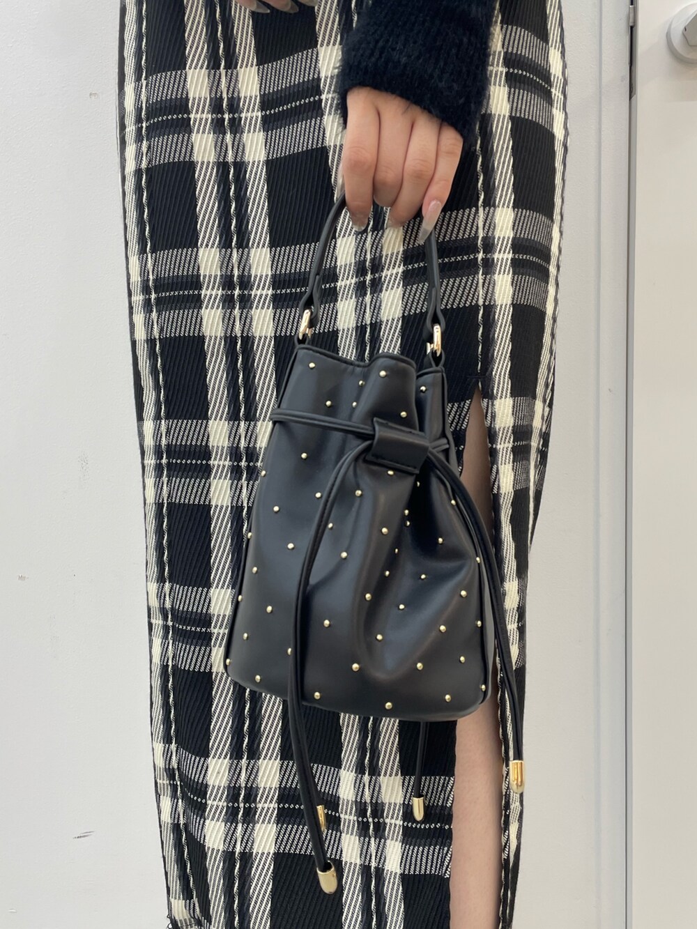 ブラック系のニット/セーター、ブラック系のスカート、ブラック系のハンドバッグを着用したレディースの夏コーディネートの7枚目の写真