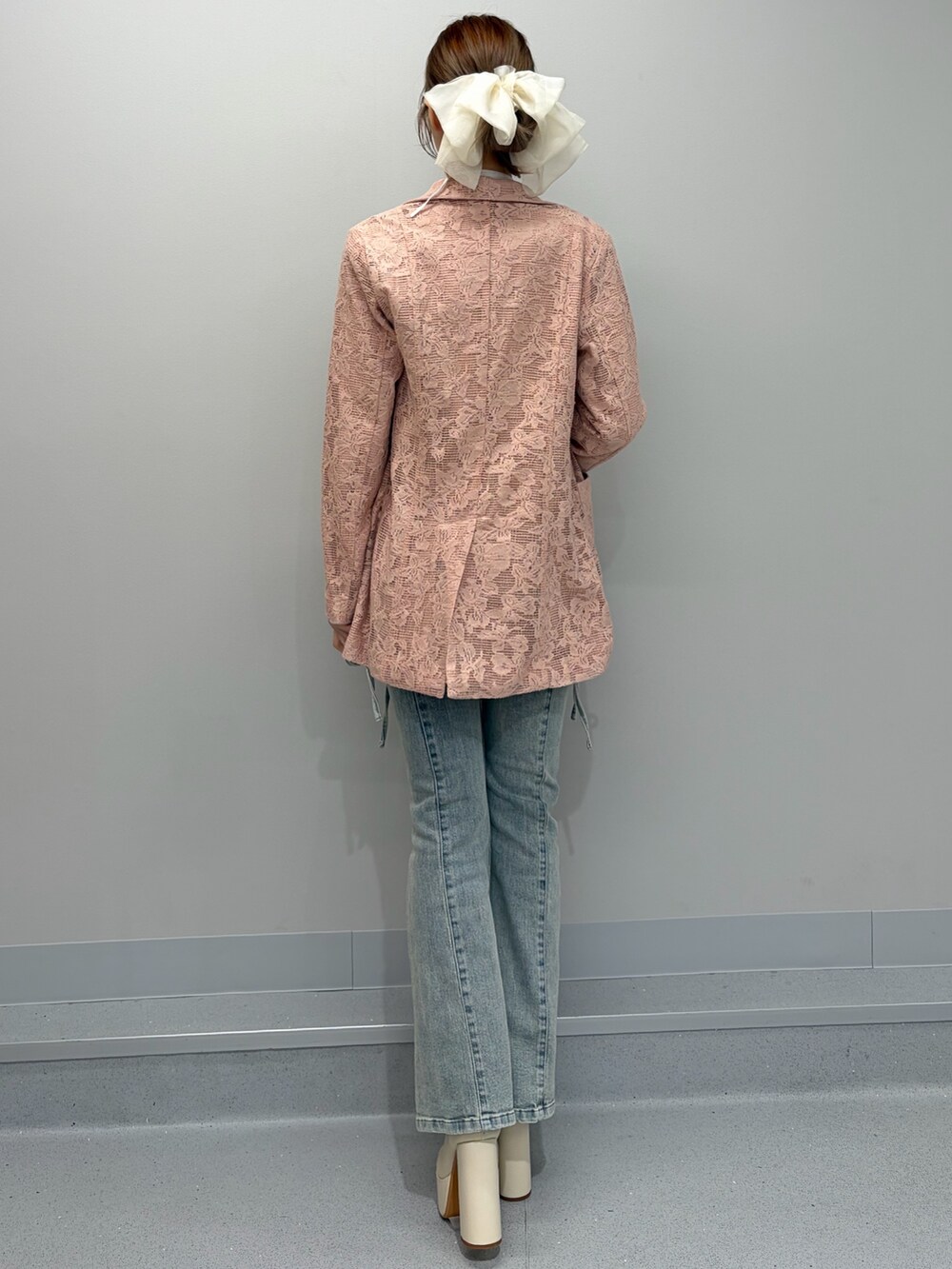 ピンク系のテーラードジャケット、ホワイト系のニット/セーター、ブルー系のデニムパンツを着用したレディースの冬コーディネートの3枚目の写真