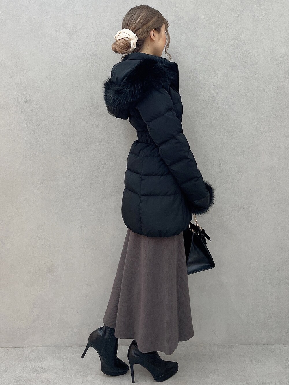 グレー系のワンピース、ブラック系のハンドバッグ、ブラック系のブーツを着用したレディースの秋コーディネートの3枚目の写真