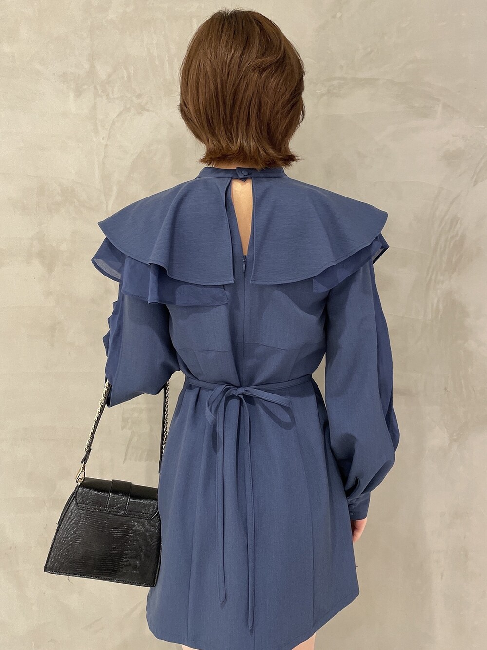 ブラック系のハンドバッグ、ブラック系のブーツ、ブルー系のワンピースを着用したレディースの冬コーディネートの5枚目の写真