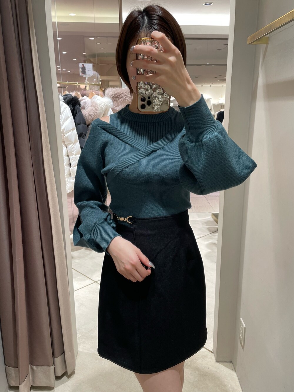 グリーン系のニット/セーター、ブラック系のスカート、ブラック系のブーツを着用したレディースの冬コーディネートの4枚目の写真