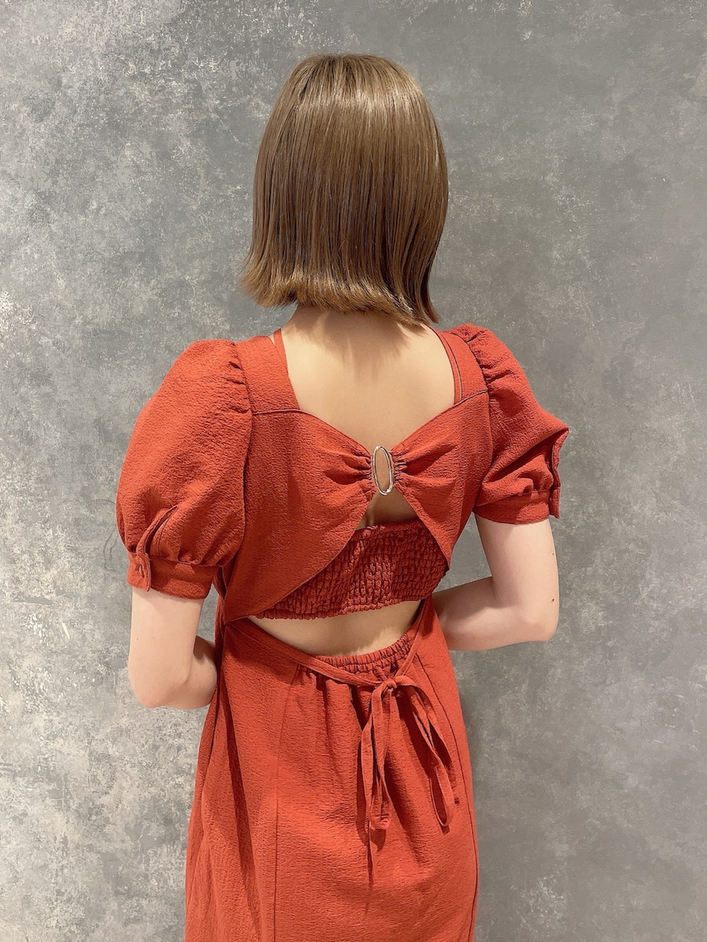 オレンジ系のワンピース、ホワイト系のサンダルを着用したレディースの春コーディネートの6枚目の写真