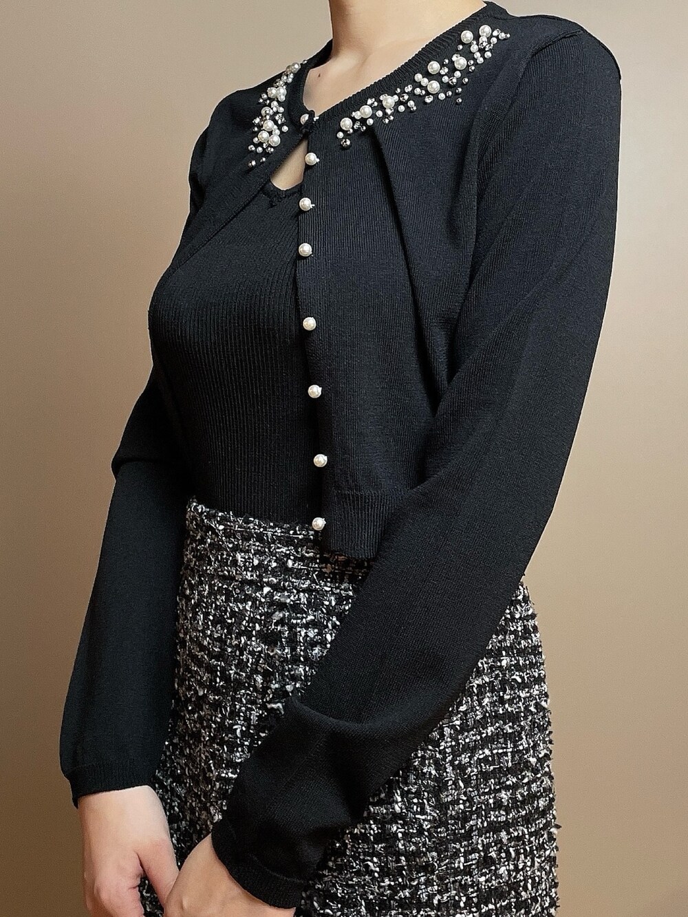 ホワイト系のハンドバッグ、ブラック系のカーディガン/ボレロ、ブラック系のスカートを着用したレディースの冬コーディネートの6枚目の写真