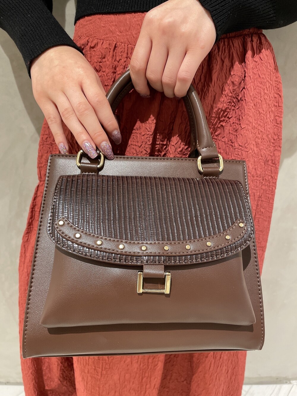 ベージュ系のダウンジャケット/コート、ブラック系のニット/セーター、ブラウン系のハンドバッグを着用したレディースの秋コーディネートの9枚目の写真