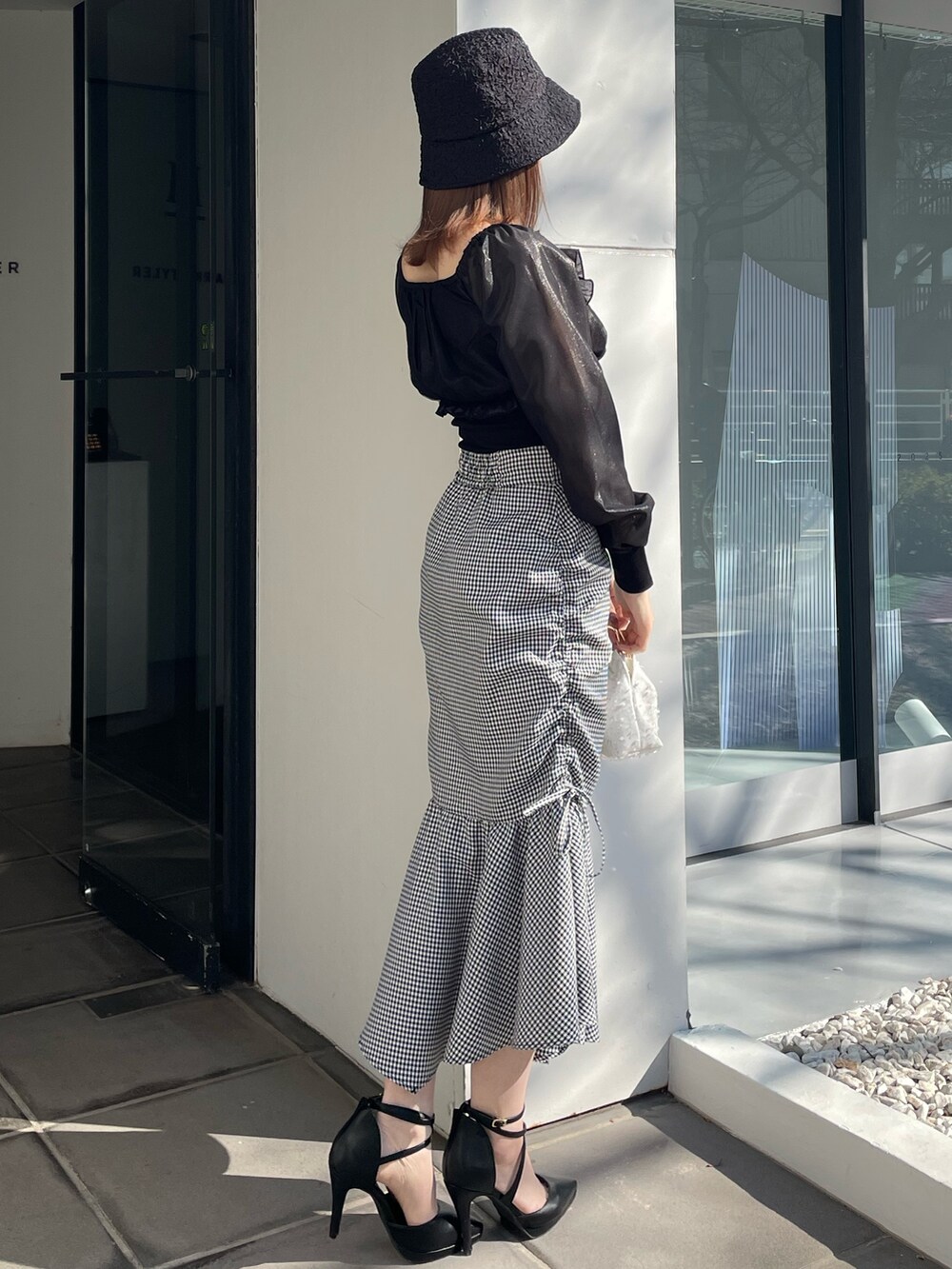 ホワイト系のハンドバッグ、ブラック系のパンプス、その他のスカートを着用したレディースの冬コーディネートの2枚目の写真