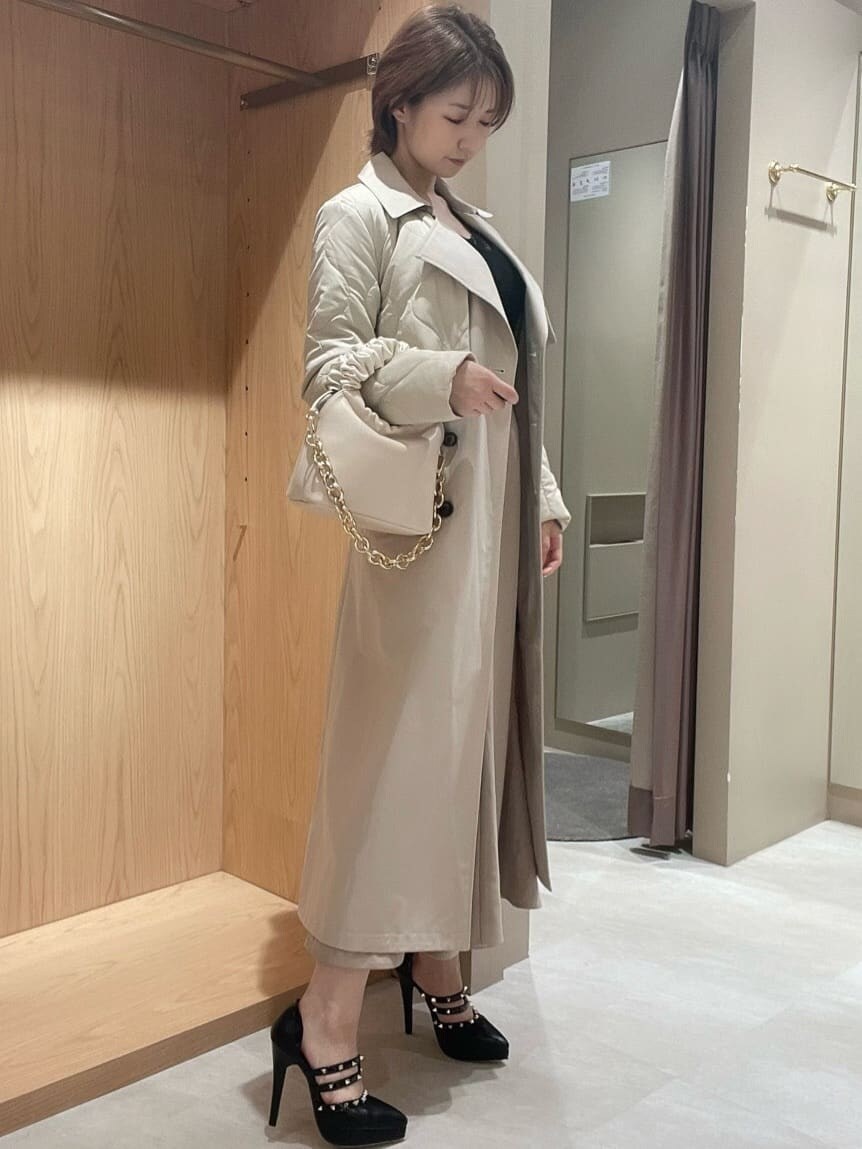 ブラック系のパンプス、ホワイト系のハンドバッグ、ホワイト系のトレンチコートを着用したレディースの秋コーディネートの2枚目の写真