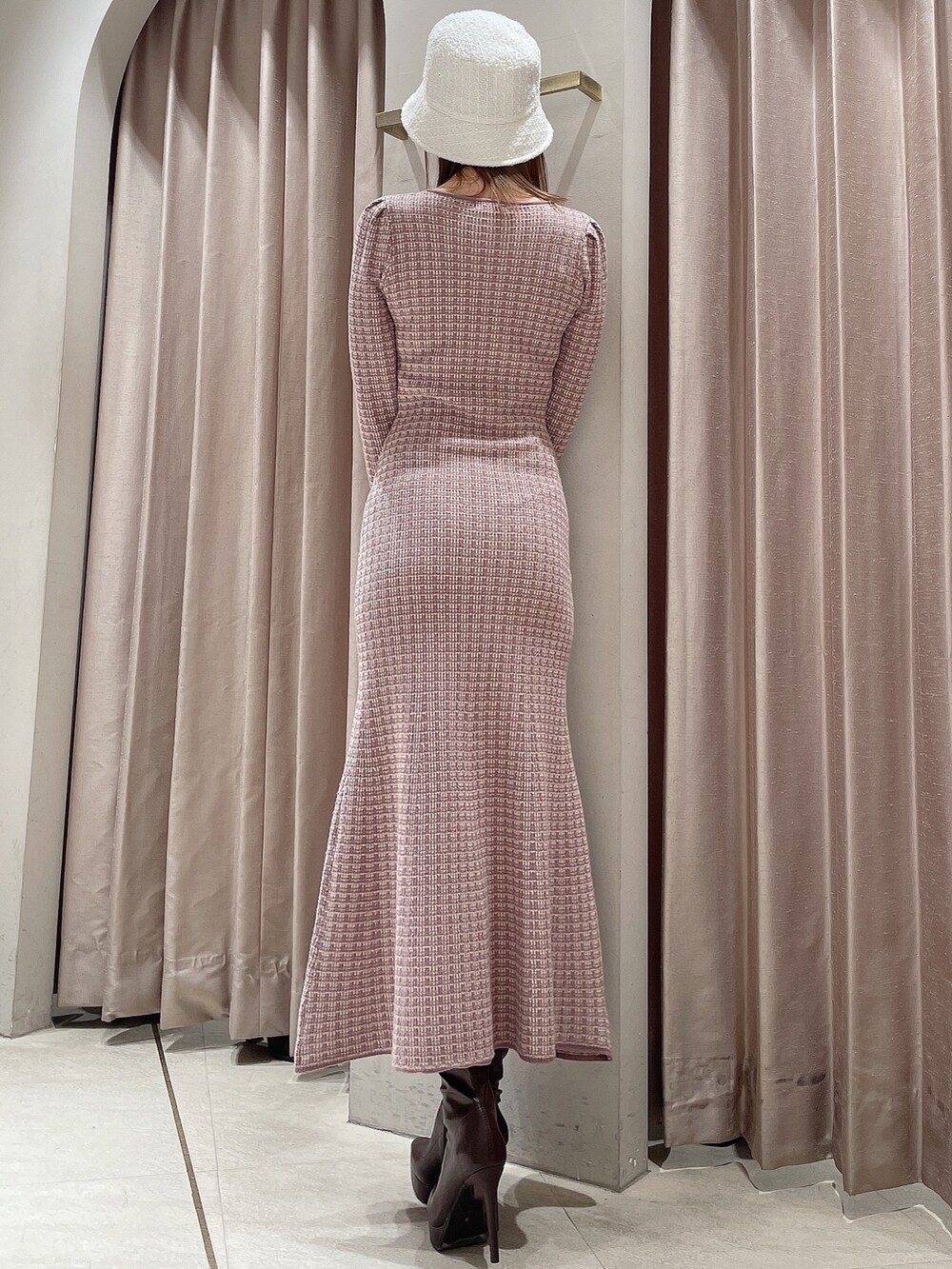 ピンク系のワンピース、ブラウン系のブーツ、ホワイト系のハットを着用したレディースの冬コーディネートの3枚目の写真