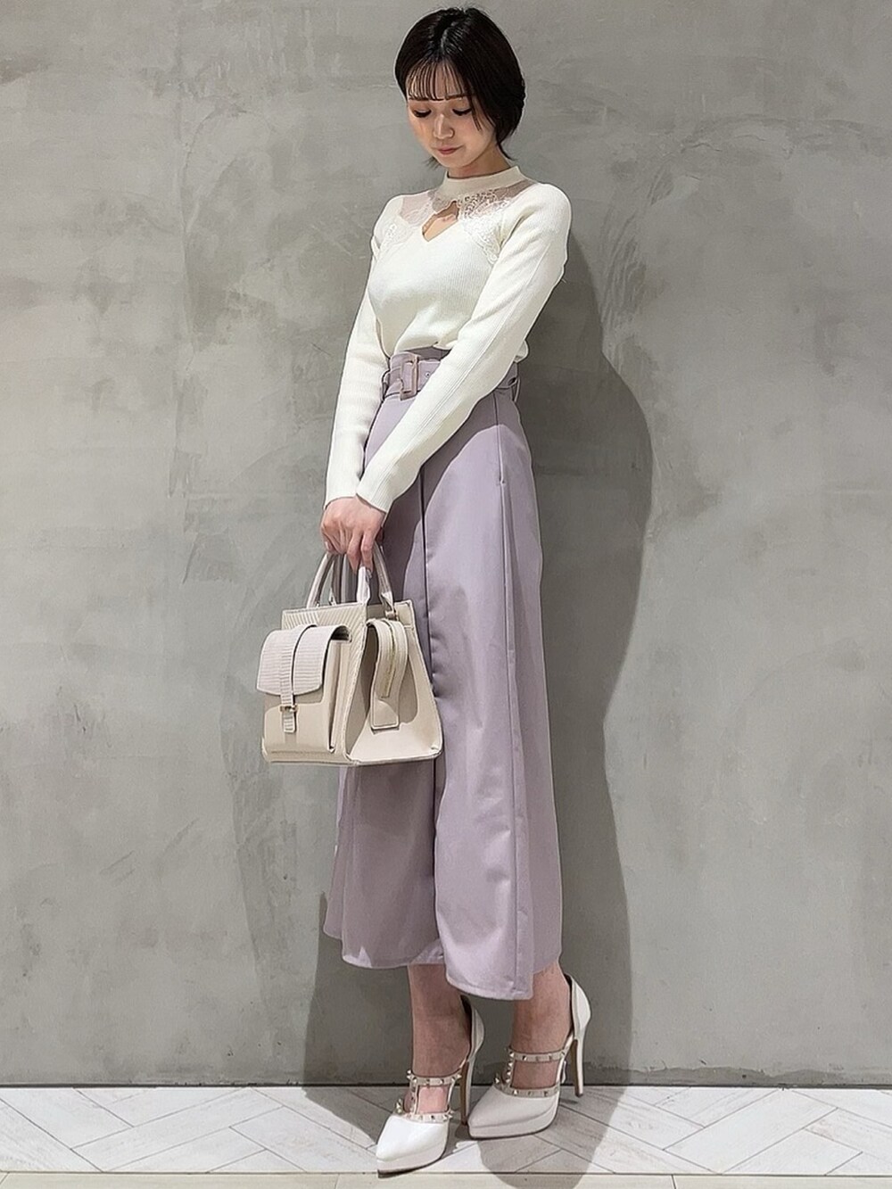 ホワイト系のニット/セーター、パープル系のスカート、ホワイト系のハンドバッグを着用したレディースの冬コーディネートの2枚目の写真