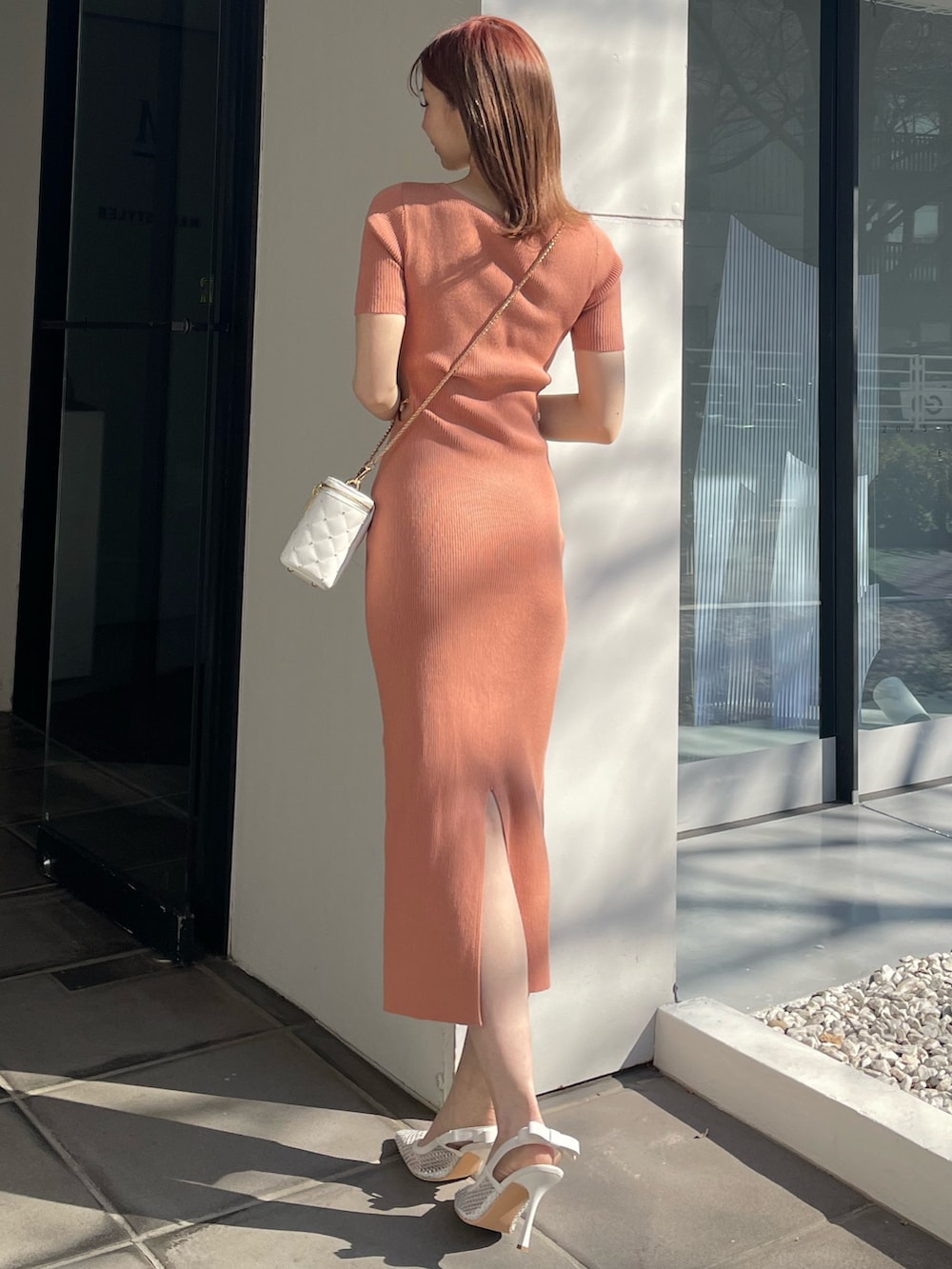 オレンジ系のワンピース、ホワイト系のショルダーバッグ、ホワイト系のパンプスを着用したレディースの冬コーディネートの3枚目の写真