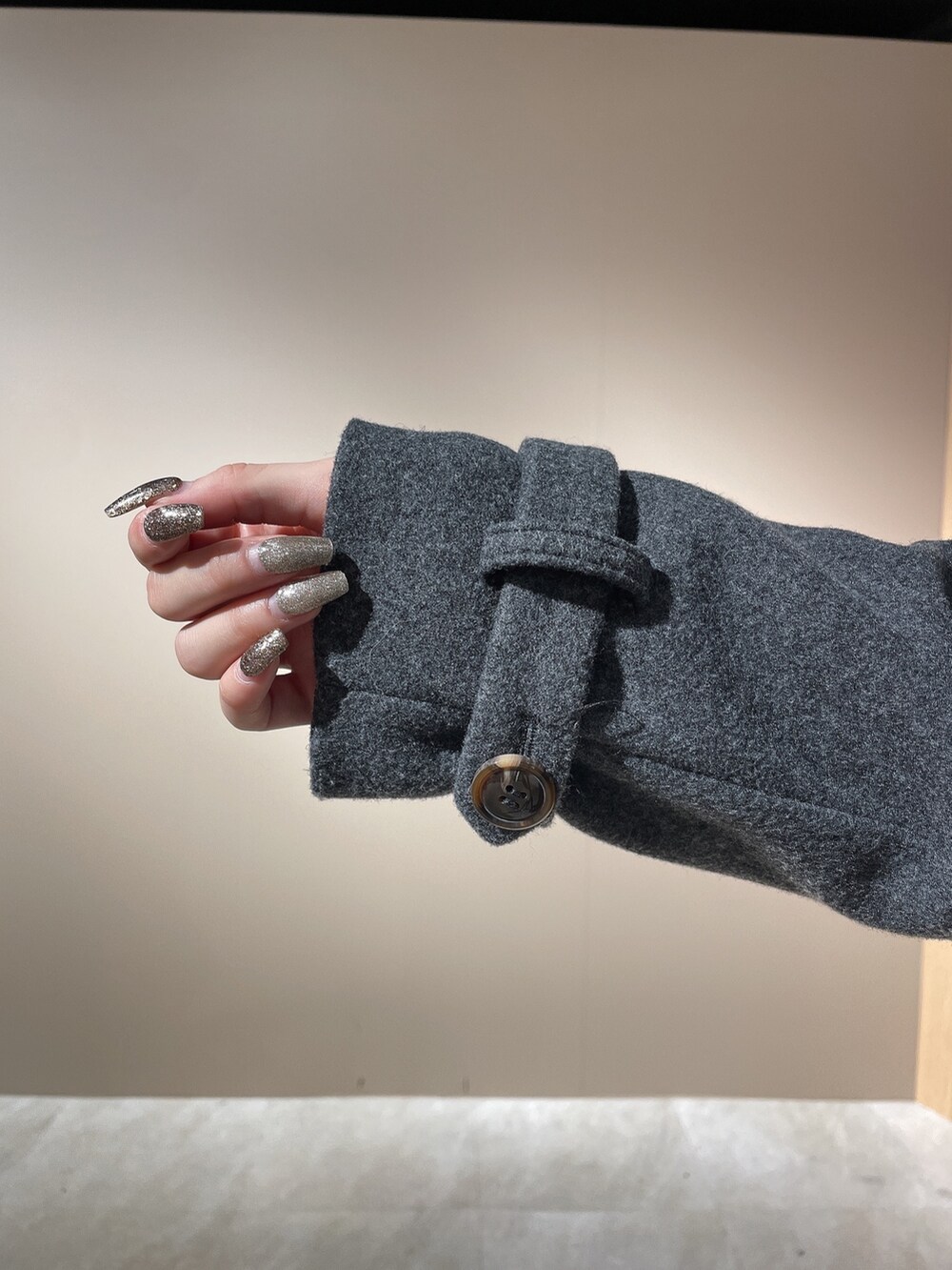 ブラック系のニット/セーター、グレー系のチェスターコート、ブラック系のブーツを着用したレディースの秋コーディネートの8枚目の写真