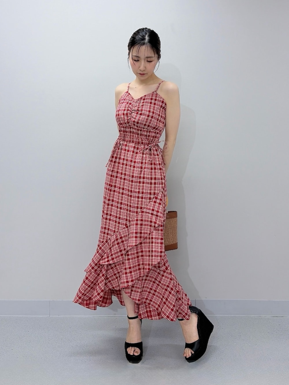 レッド系のワンピース、ブラウン系のハンドバッグ、ブラック系のサンダルを着用したレディースの夏コーディネートの3枚目の写真