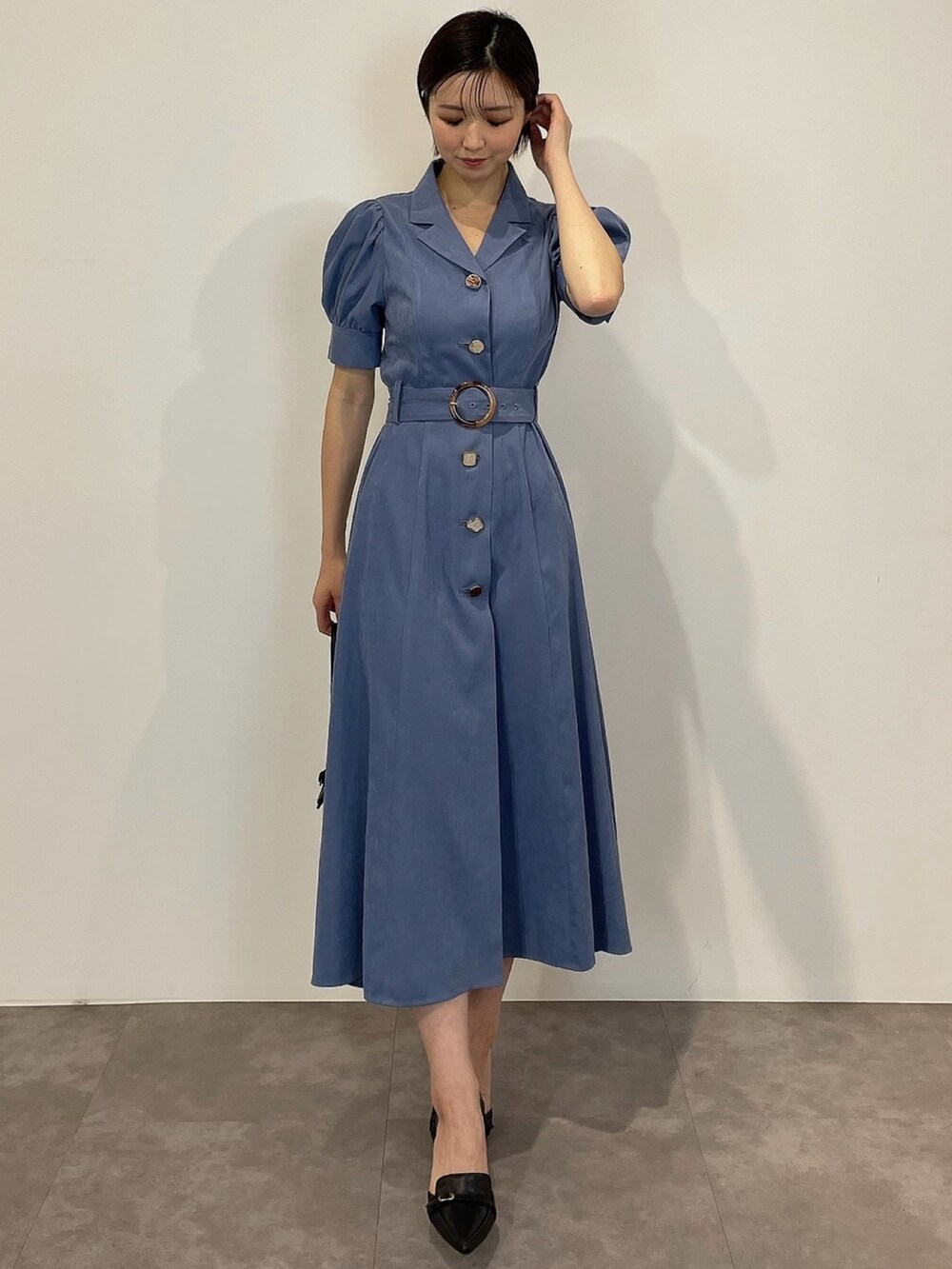 ブルー系のワンピース、ブラック系のパンプス、ブラック系のハンドバッグを着用したレディースの冬コーディネートの2枚目の写真