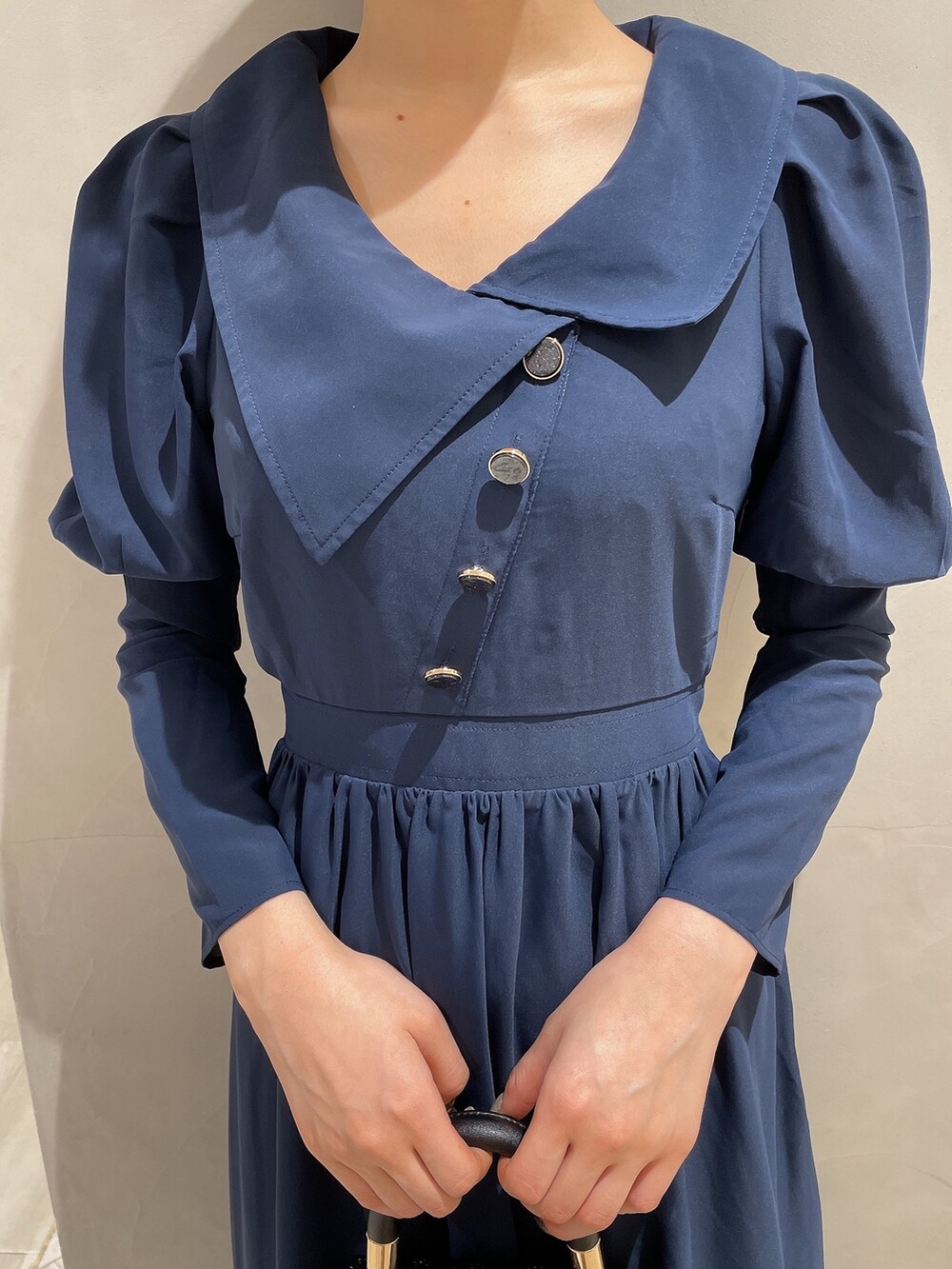 ブラック系のハンドバッグ、ブルー系のワンピース、ブラック系のパンプスを着用したレディースの冬コーディネートの5枚目の写真