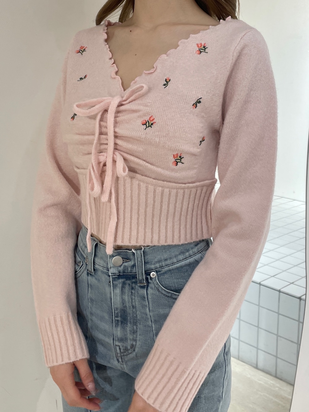 ピンク系のニット/セーター、ブルー系のデニムパンツ、ホワイト系のブーツを着用したレディースの冬コーディネートの5枚目の写真