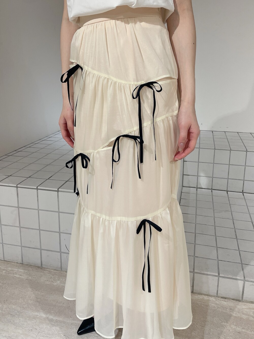 ホワイト系のTシャツ/カットソー、ホワイト系のスカート、ブラック系のパンプスを着用したレディースの夏コーディネートの6枚目の写真