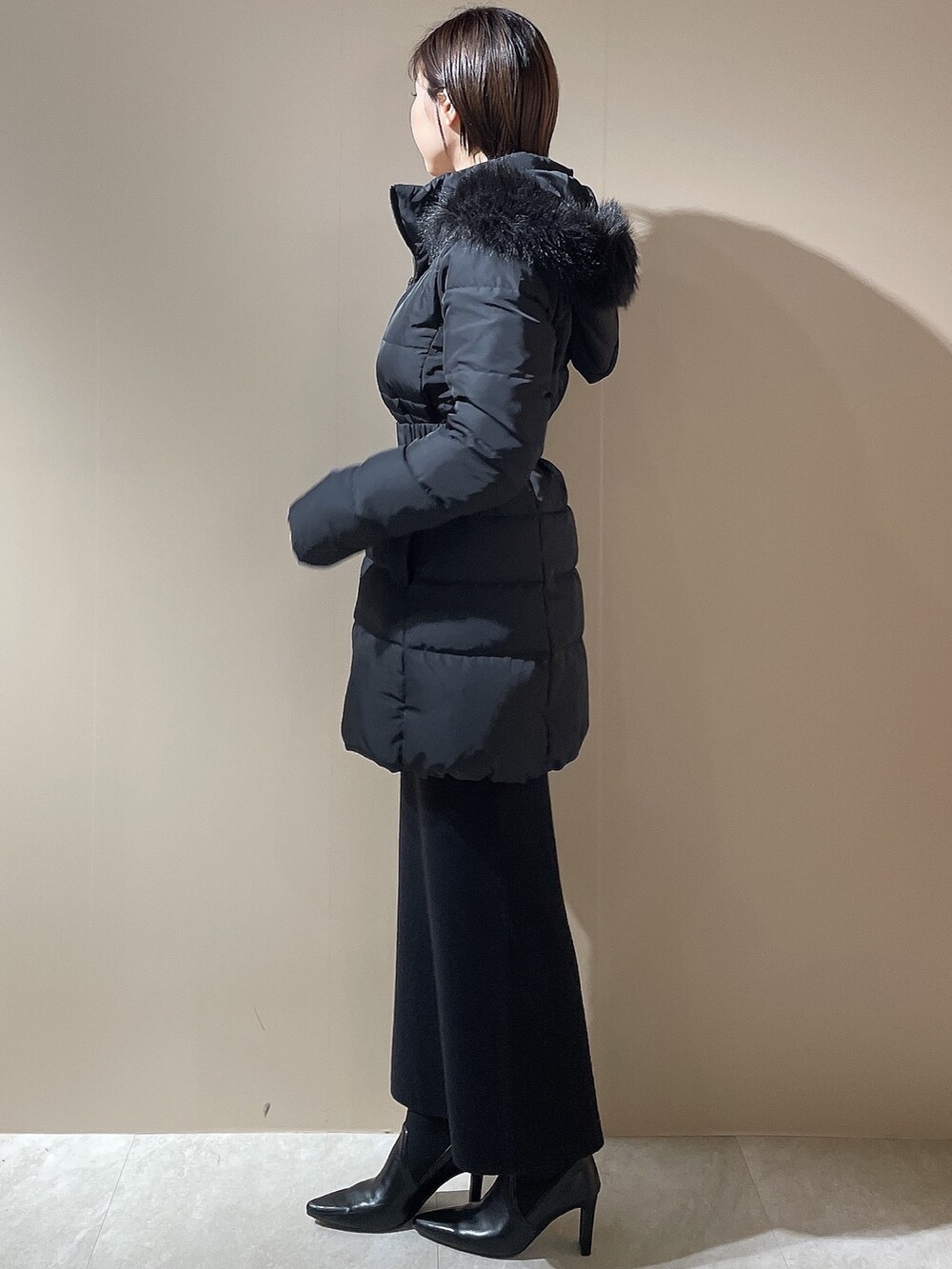 ブラック系のダウンジャケット/コート、ブラック系のワンピース、ブラック系のブーツを着用したレディースの秋コーディネートの2枚目の写真