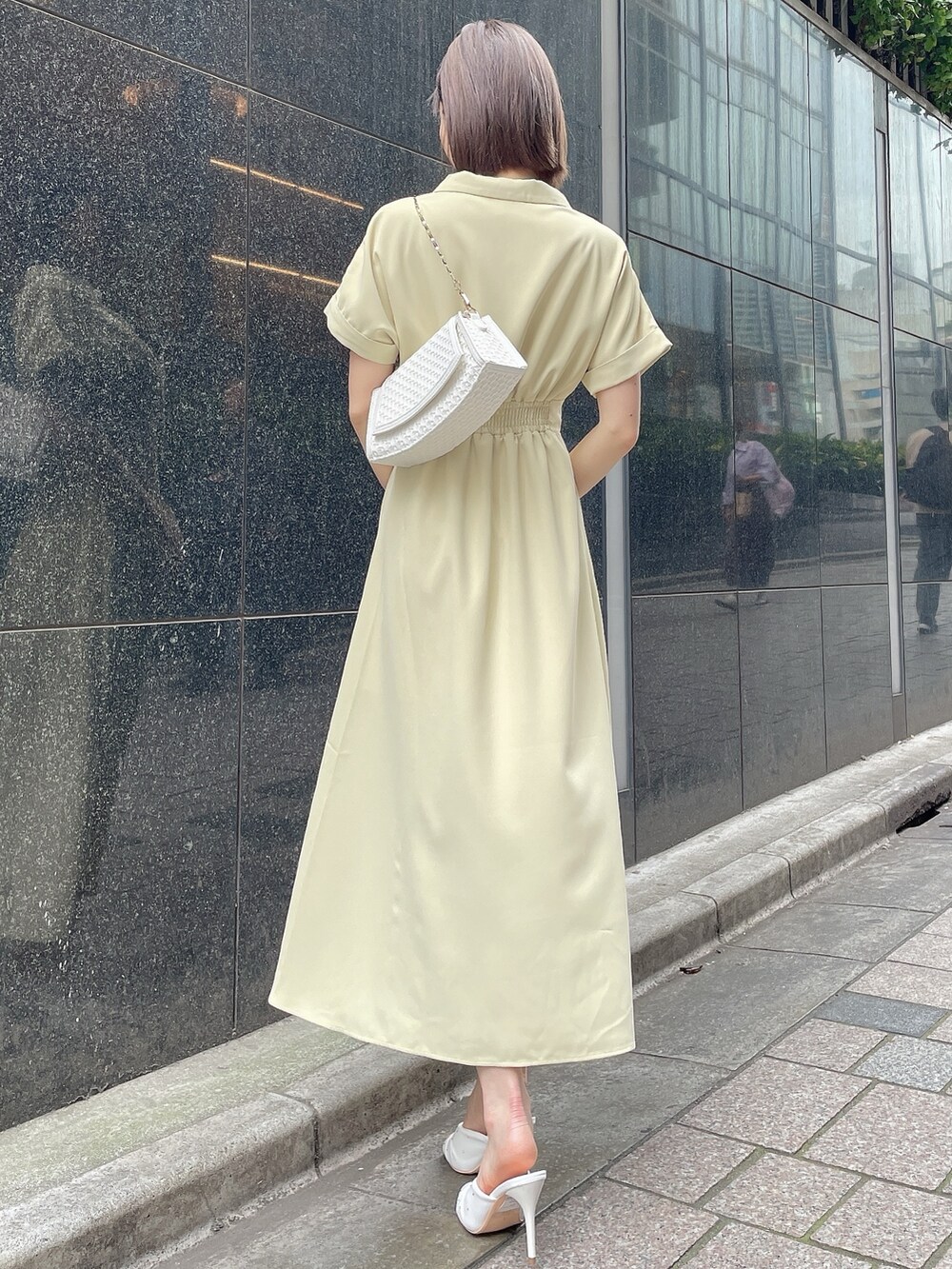 イエロー系のワンピース、ホワイト系のサンダル、ホワイト系のハンドバッグを着用したレディースの春コーディネートの4枚目の写真