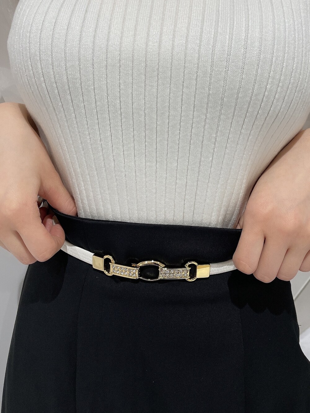 ホワイト系のニット/セーター、ブラック系のスカート、ブラック系のパンプスを着用したレディースの春コーディネートの5枚目の写真