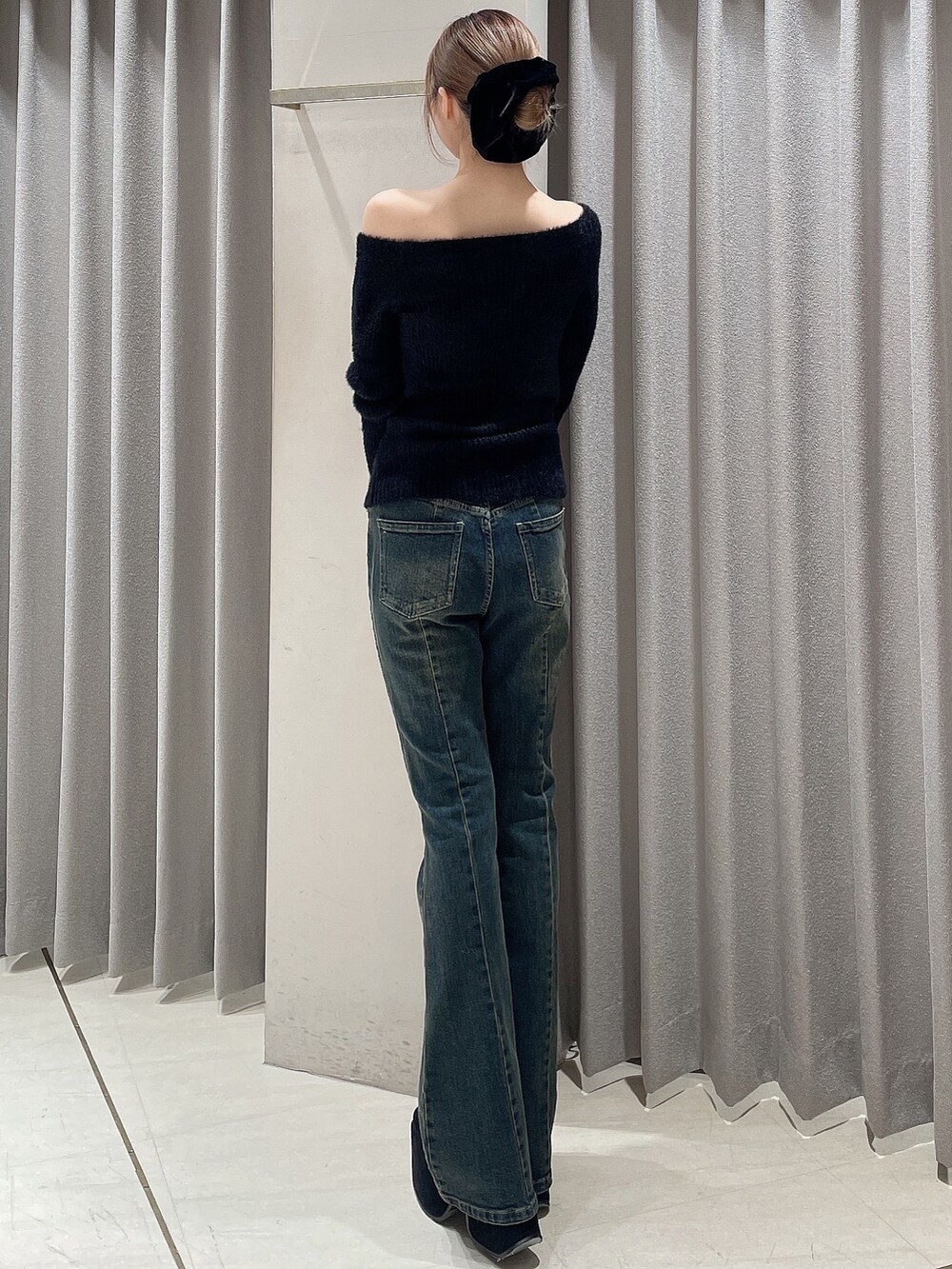 ブルー系のデニムパンツ、ブラック系のニット/セーター、ブラック系のブーツを着用したレディースの秋コーディネートの3枚目の写真