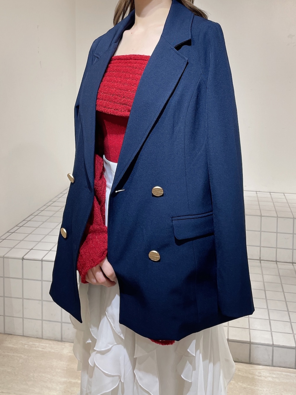 ブルー系のテーラードジャケット、レッド系のニット/セーター、ホワイト系のスカートを着用したレディースの冬コーディネートの8枚目の写真