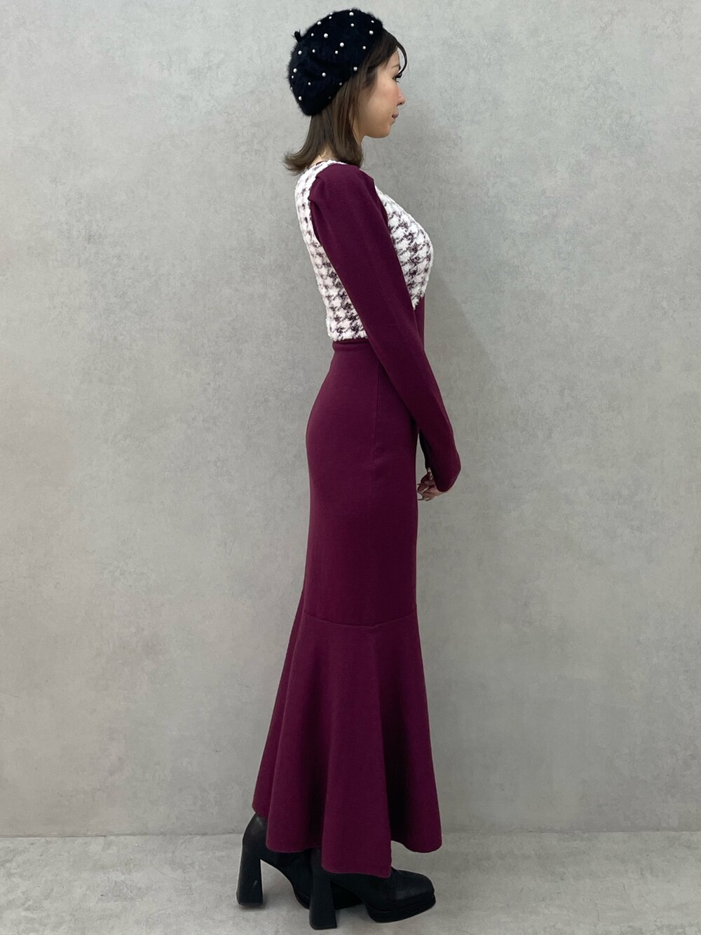 レッド系のワンピース、ブラック系のブーツ、ブラック系のハンチング/ベレー帽を着用したレディースの秋コーディネートの2枚目の写真