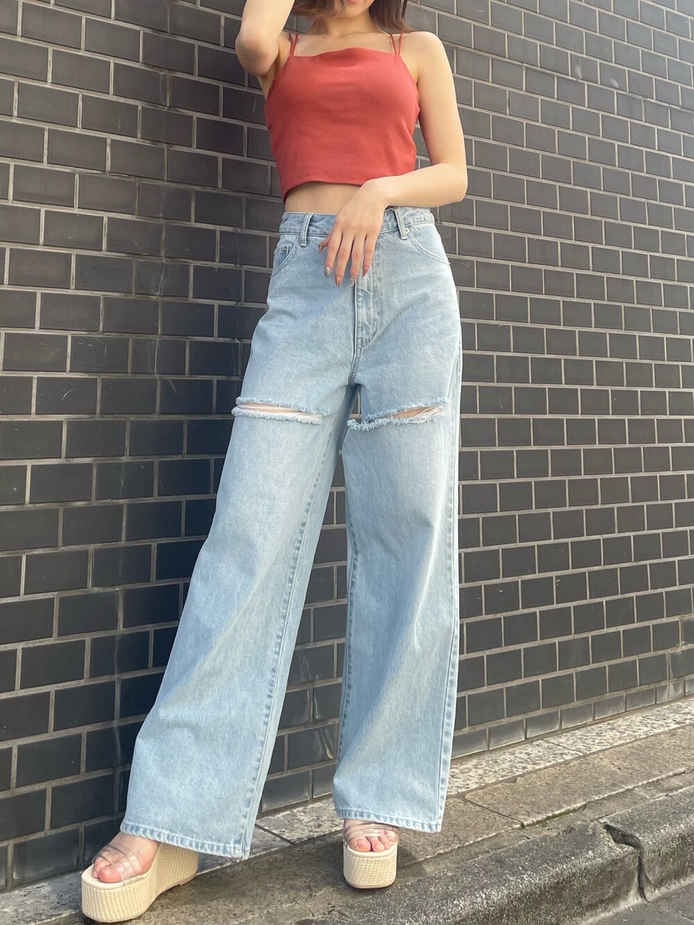 オレンジ系のキャミソール、ブルー系のデニムパンツ、ホワイト系のサンダルを着用したレディースの春コーディネートの3枚目の写真