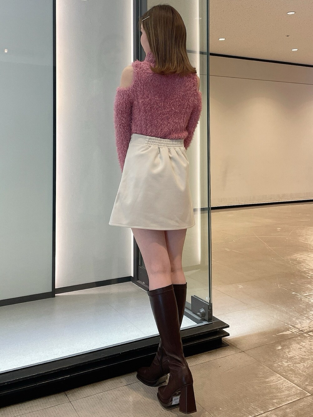 ピンク系のニット/セーター、ホワイト系のスカート、ブラウン系のブーツを着用したレディースの冬コーディネートの4枚目の写真