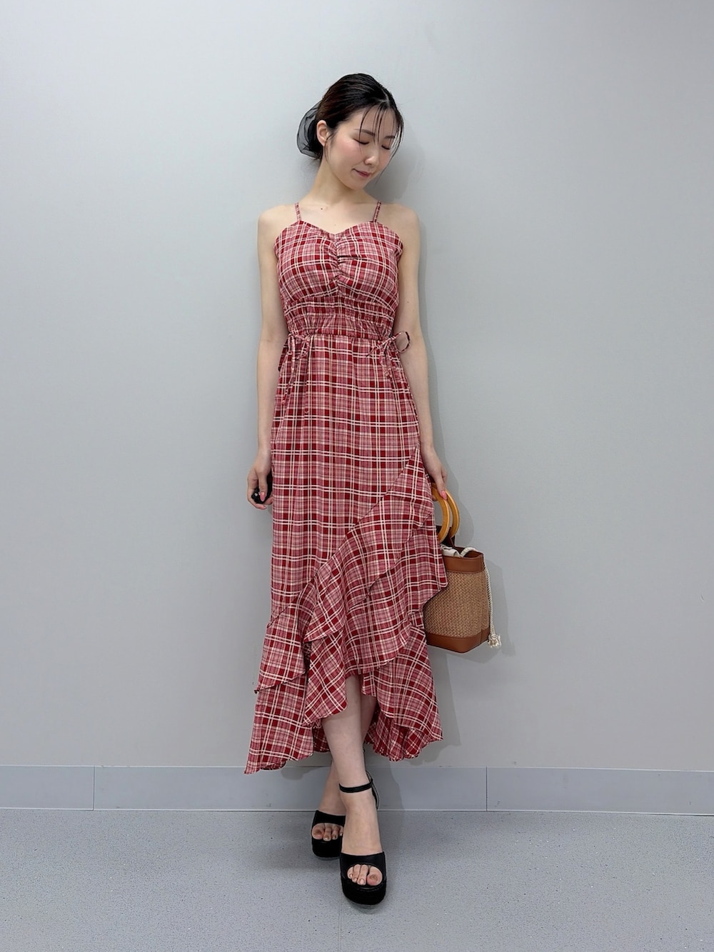 レッド系のワンピース、ブラウン系のハンドバッグ、ブラック系のサンダルを着用したレディースの夏コーディネートの2枚目の写真