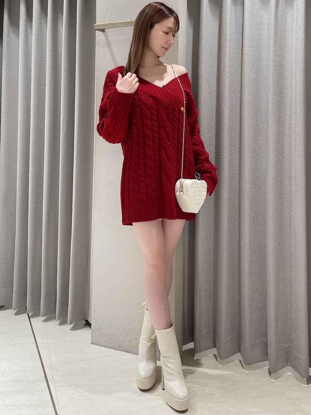 レッド系のニット/セーター、ホワイト系のスカート、ホワイト系のショルダーバッグを着用したレディースの冬コーディネートの2枚目の写真