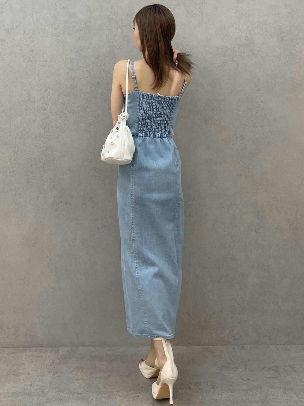 ブルー系のデニムジャケット、ブルー系のワンピース、ホワイト系のハンドバッグを着用したレディースの春コーディネートの6枚目の写真