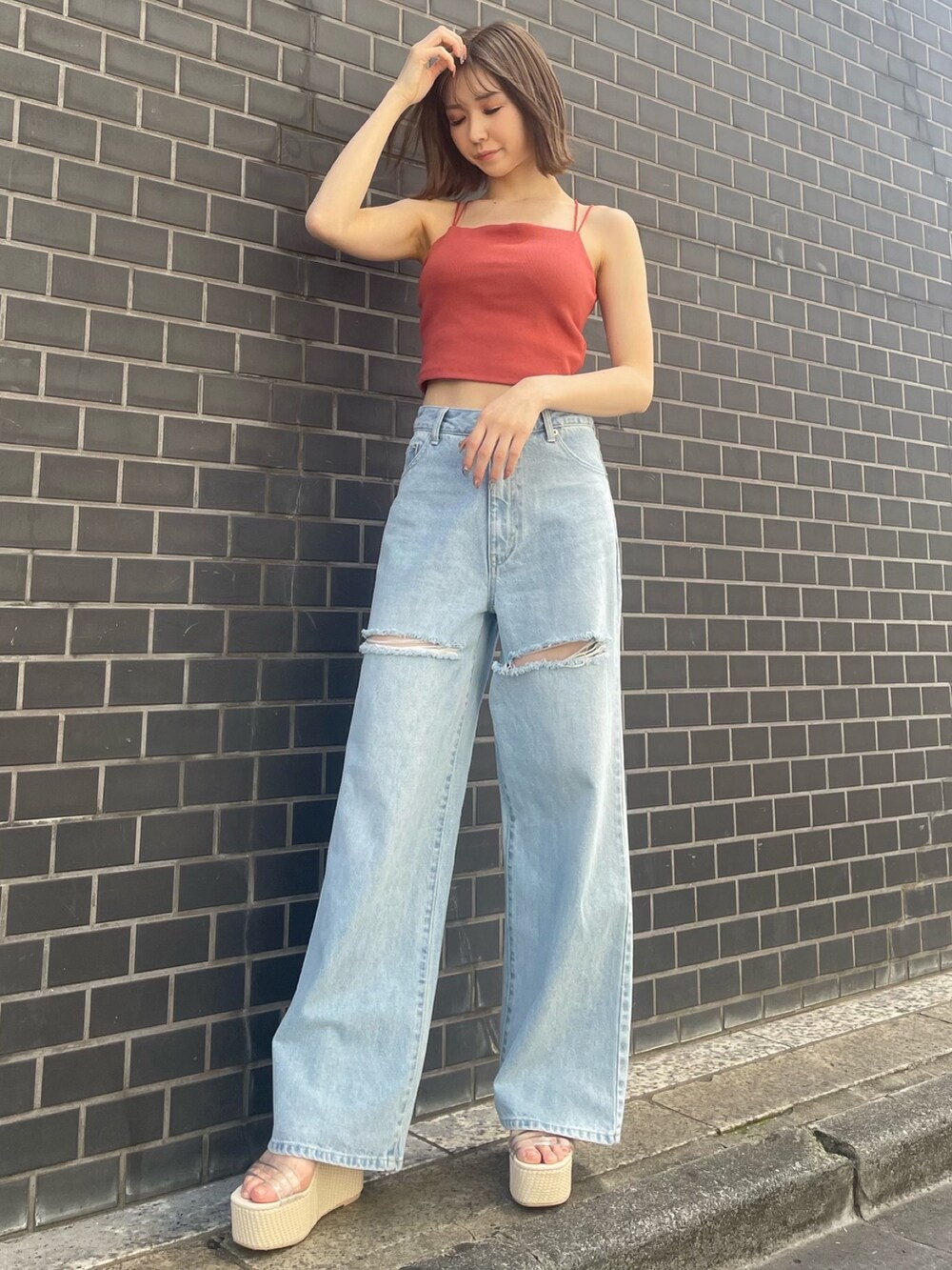 オレンジ系のキャミソール、ブルー系のデニムパンツ、ホワイト系のサンダルを着用したレディースの春コーディネートの2枚目の写真