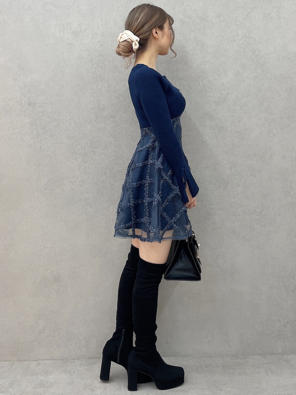 ブルー系のワンピース、ブラック系のハンドバッグ、ブラック系のブーツを着用したレディースの秋コーディネートの3枚目の写真