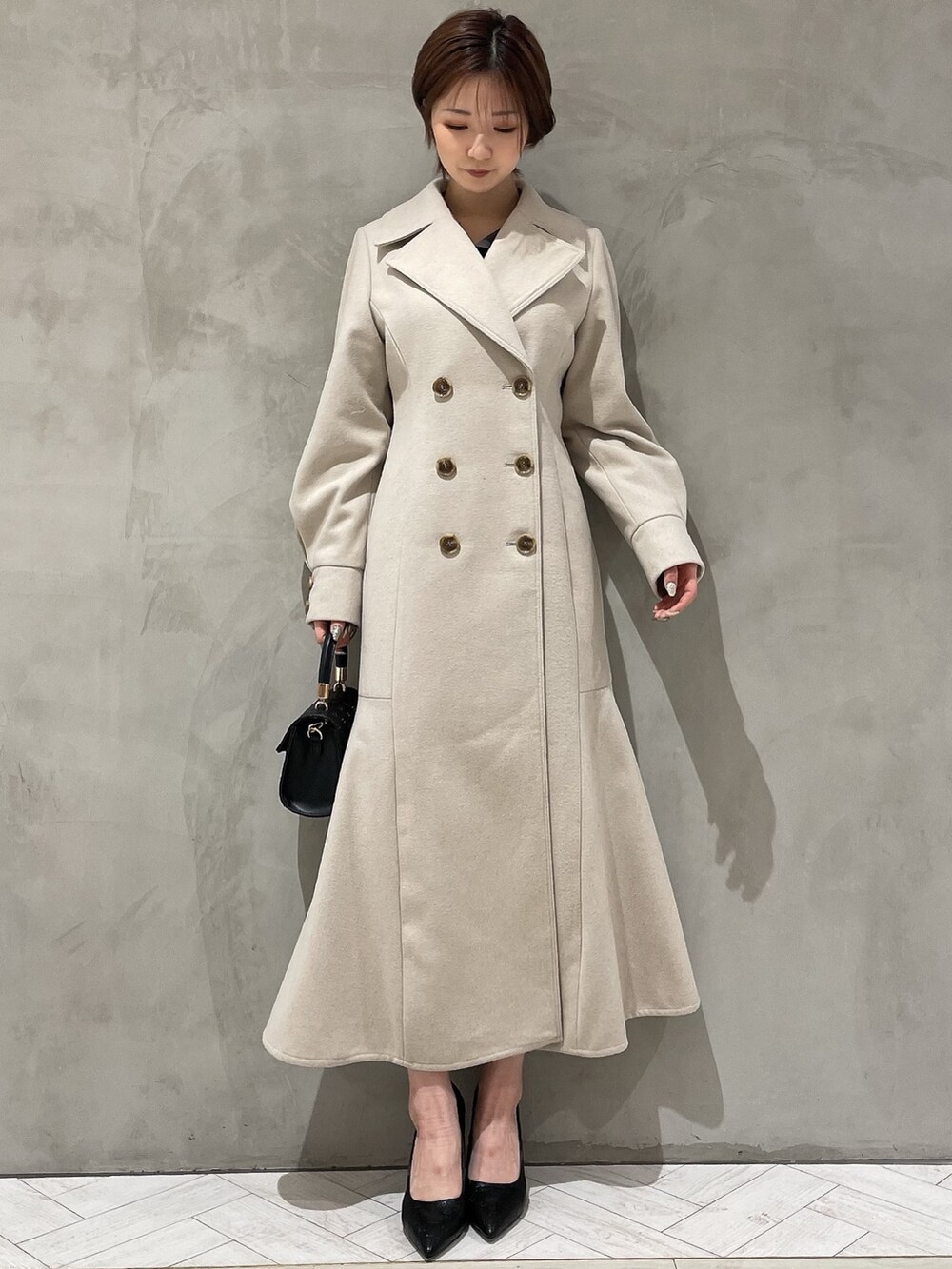 ベージュ系のその他アウター、グレー系のワンピース、ブラック系のハンドバッグを着用したレディースの冬コーディネートの2枚目の写真