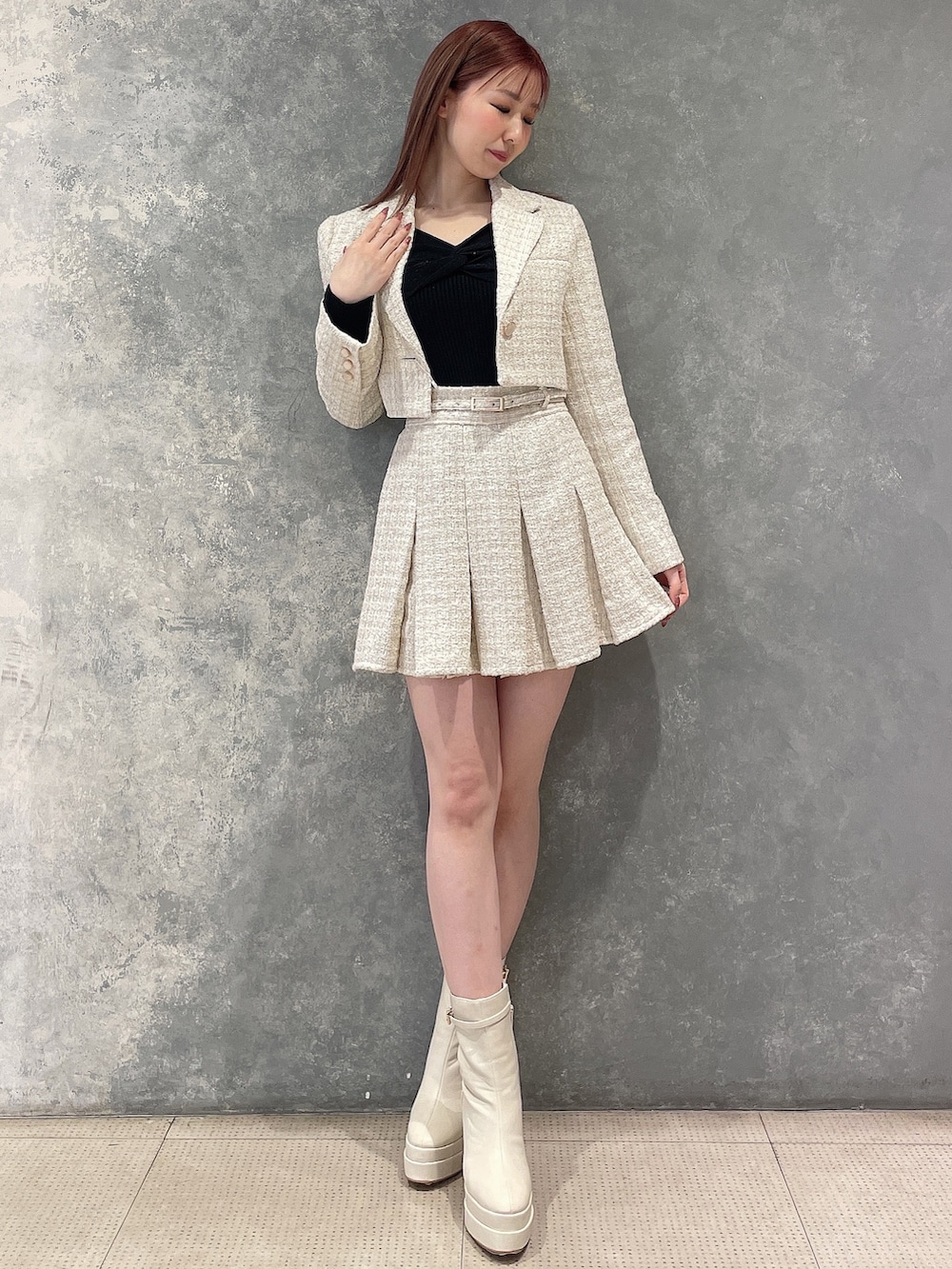 ホワイト系のテーラードジャケット、ホワイト系のスカート、ブラック系のニット/セーターを着用したレディースの冬コーディネートの2枚目の写真