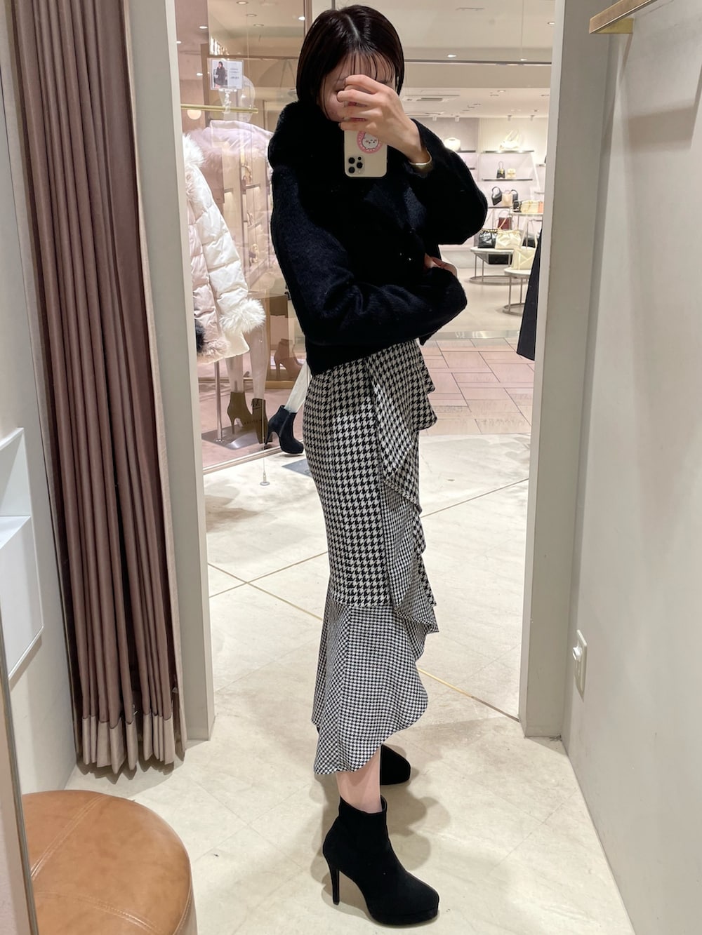 ブラック系のその他アウター、ホワイト系のニット/セーター、その他のスカートを着用したレディースの秋コーディネートの2枚目の写真