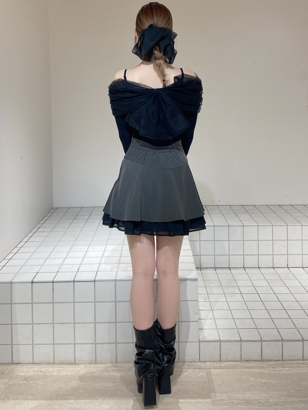 グレー系のスカート、ブラック系のニット/セーター、ブラック系のブーツを着用したレディースの春コーディネートの3枚目の写真