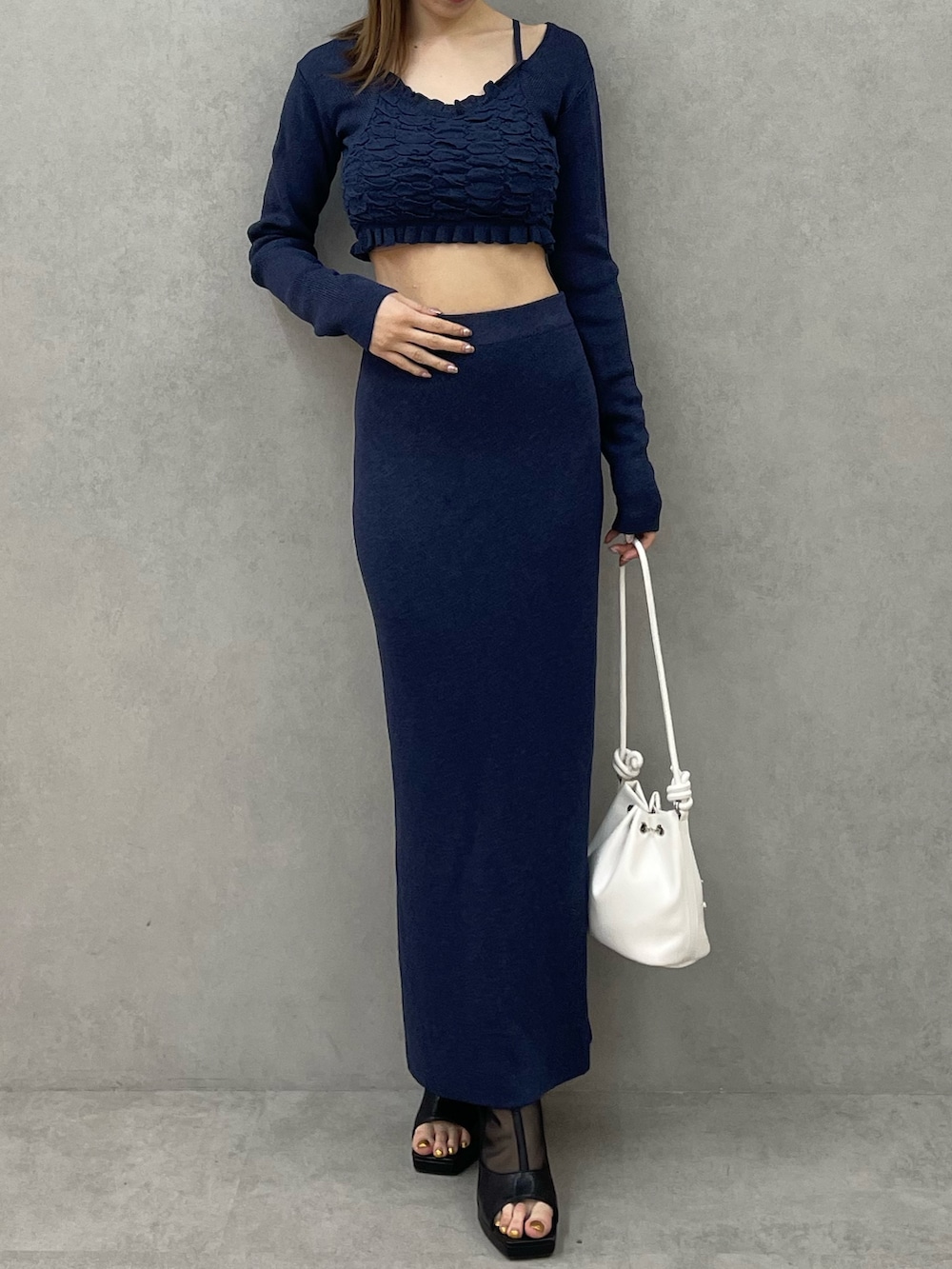 ブルー系のニット/セーター、ブルー系のスカート、ホワイト系のハンドバッグを着用したレディースの春コーディネートの3枚目の写真