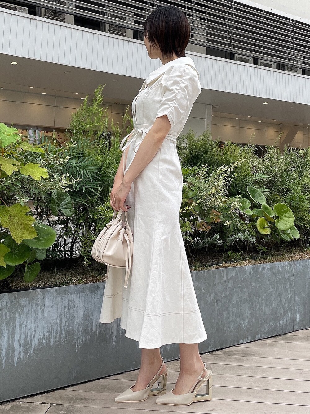 ホワイト系のワンピース、ホワイト系のハンドバッグ、ベージュ系のサンダルを着用したレディースの夏コーディネートの3枚目の写真