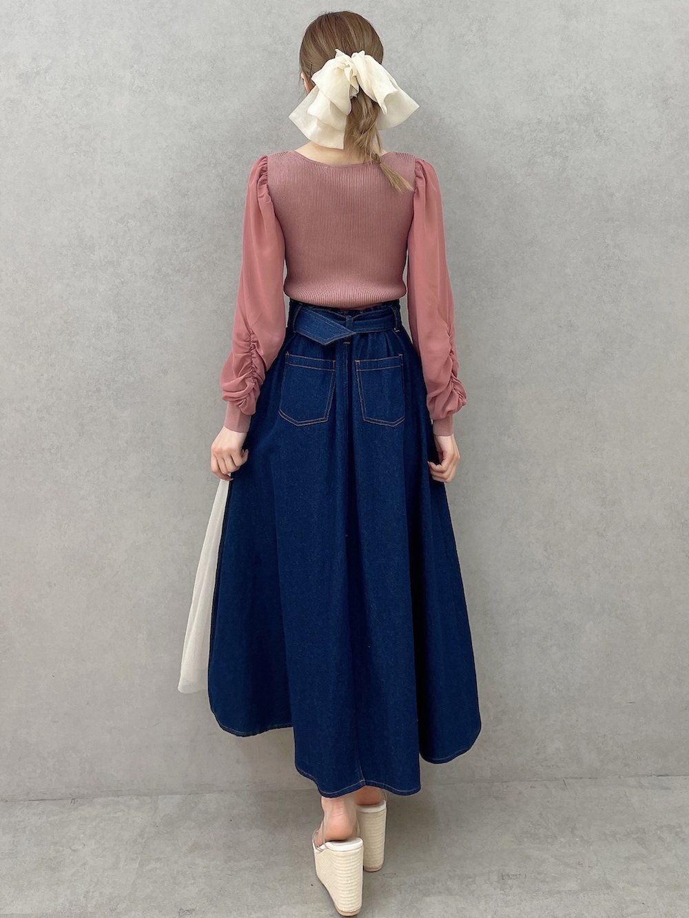 ピンク系のニット/セーター、ブルー系のスカート、ホワイト系のサンダルを着用したレディースの春コーディネートの5枚目の写真