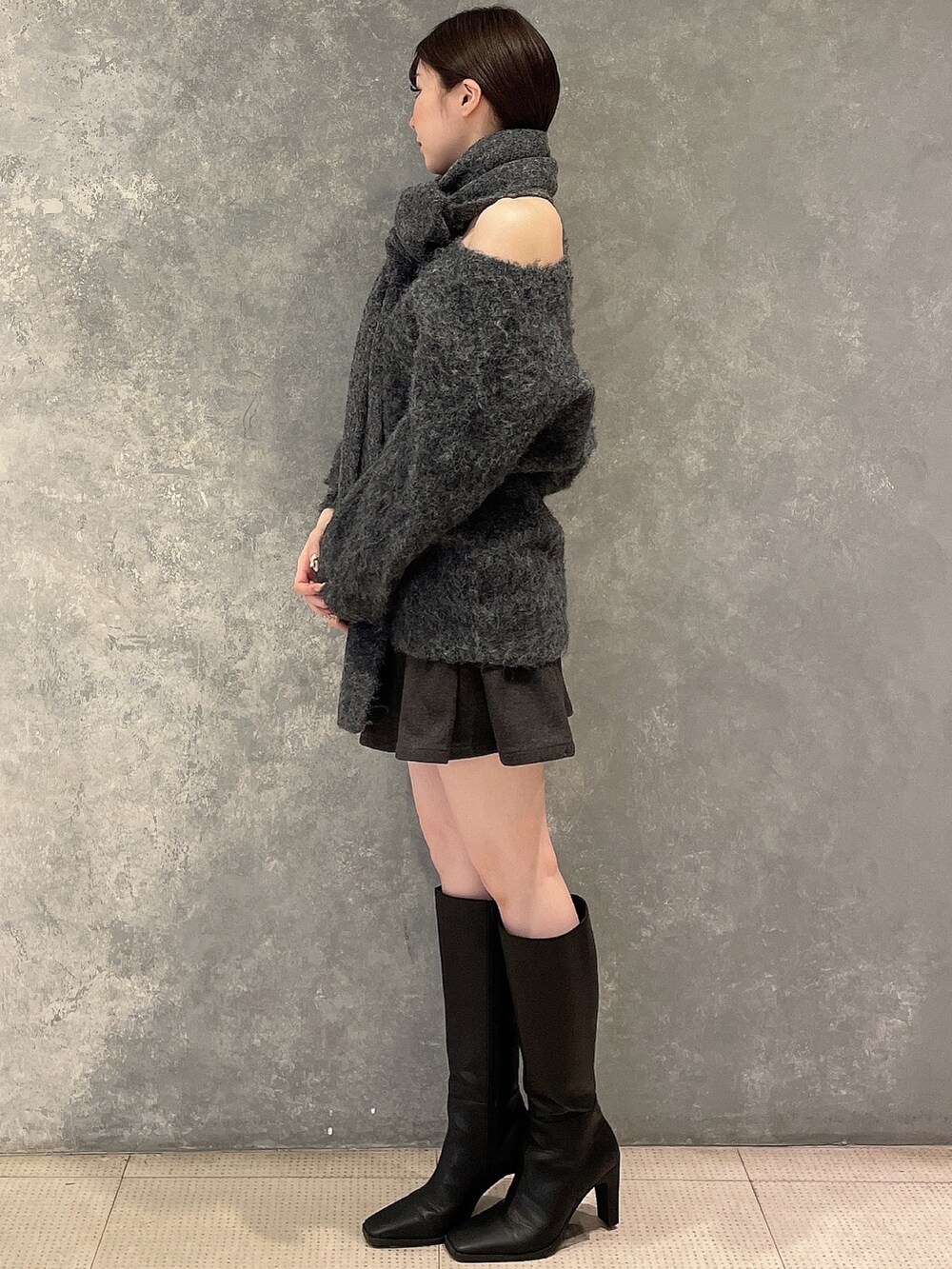 グレー系のワンピース、グレー系のスカート、ブラック系のブーツを着用したレディースの秋コーディネートの2枚目の写真