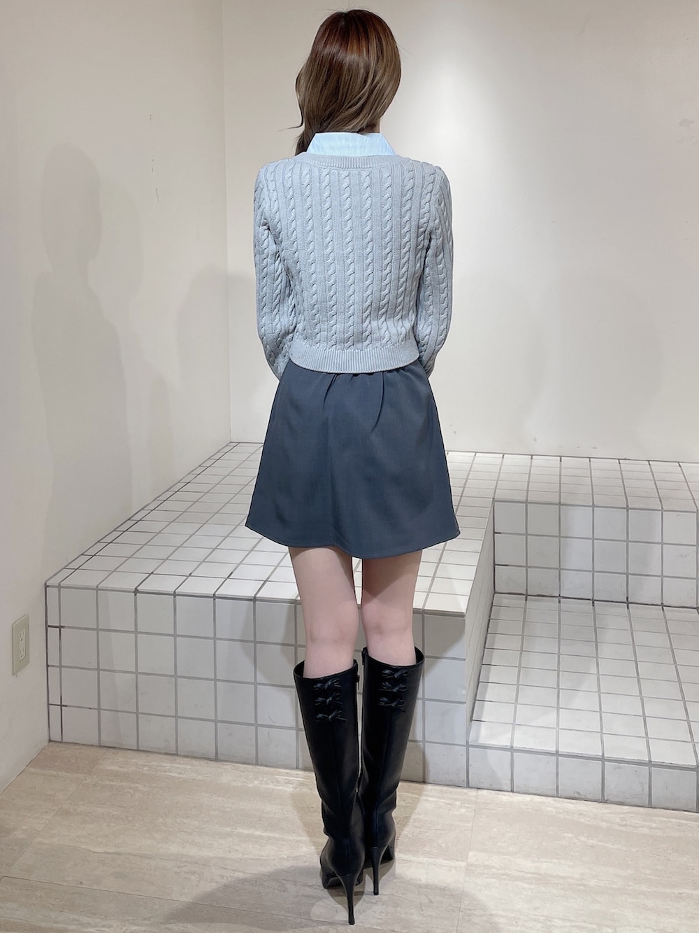 グレー系のニット/セーター、グレー系のスカート、ブラック系のブーツを着用したレディースの冬コーディネートの4枚目の写真